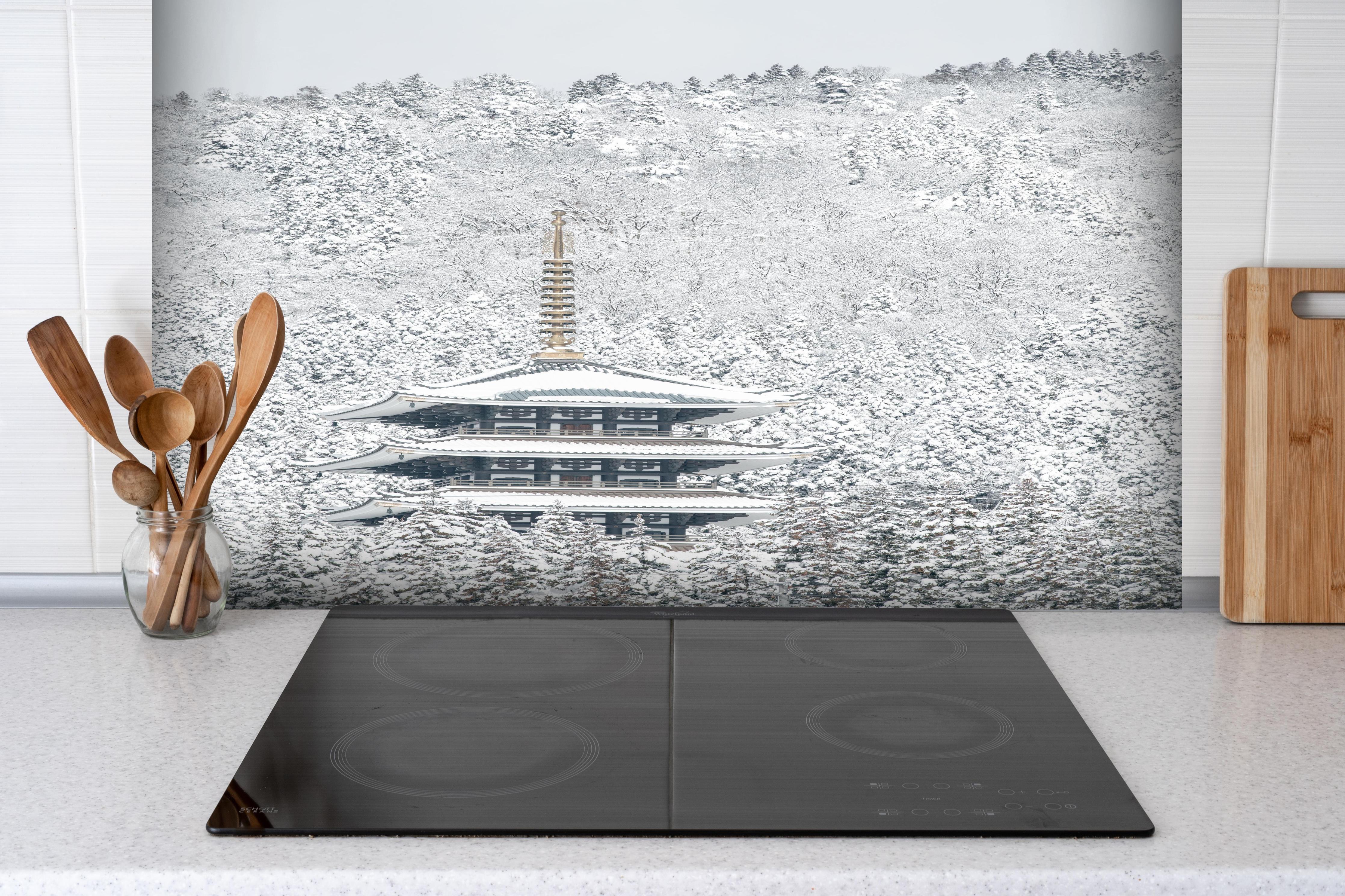 Spritzschutz - Winterlicher Turm - Buddismus hinter einem Cerankochfeld zwischen Holz-Kochutensilien