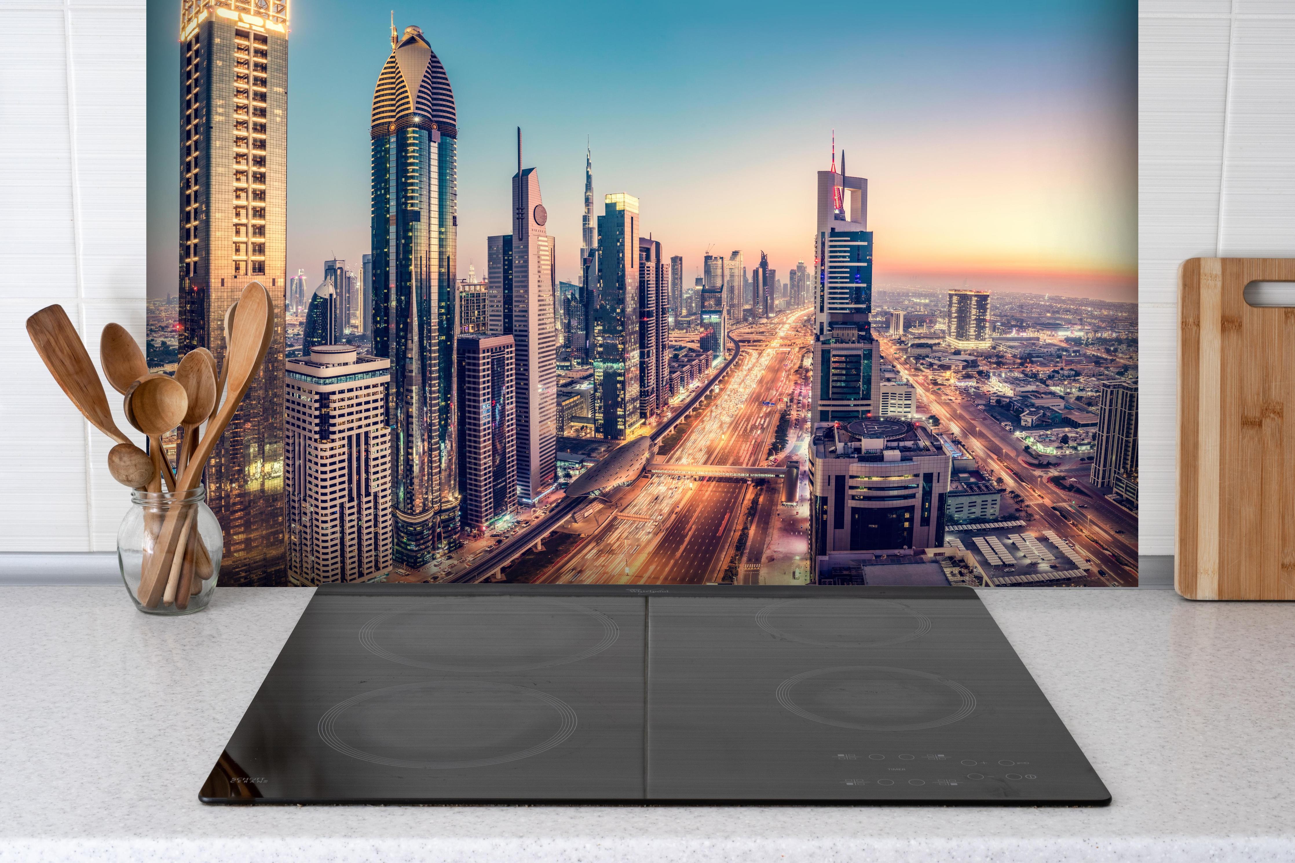Spritzschutz - Wolkenkratzer - Hochhäuser in der Innenstadt von Dubai hinter einem Cerankochfeld zwischen Holz-Kochutensilien