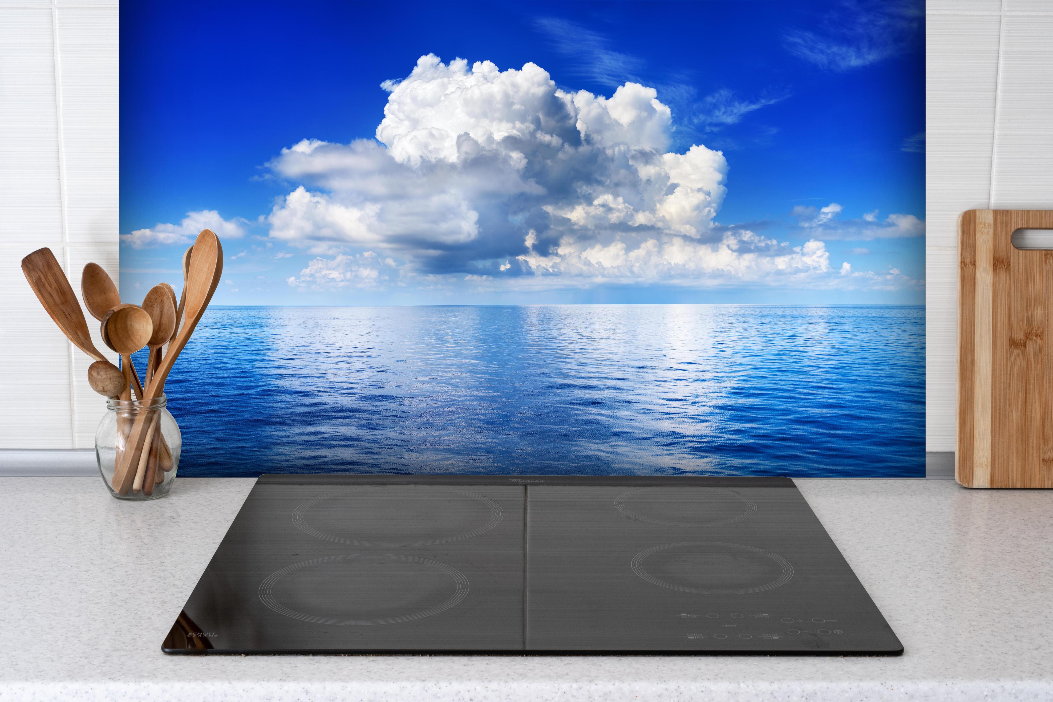 Spritzschutz - Wolkenkulisse über dem Ozean hinter einem Cerankochfeld zwischen Holz-Kochutensilien