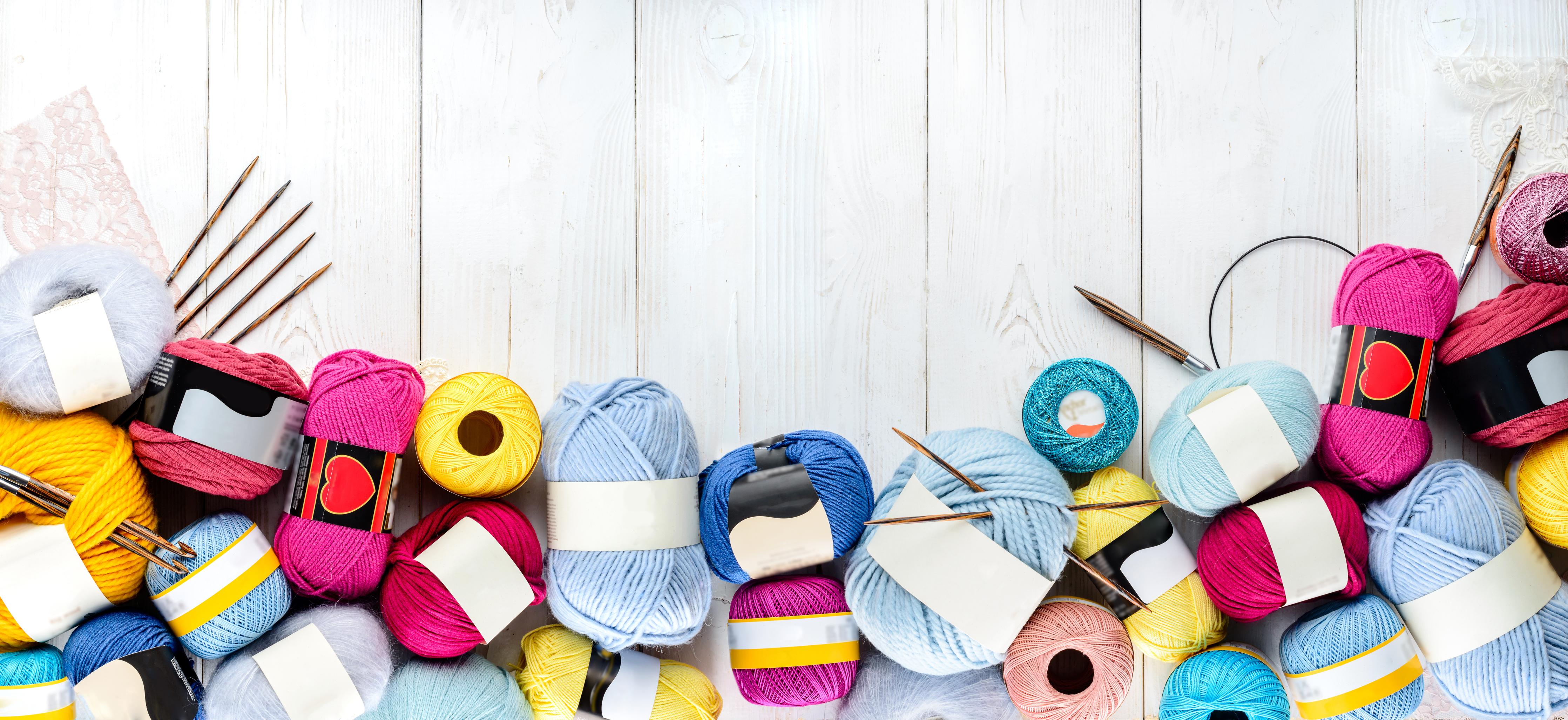 Spritzschutz-Wolle und Stricknadeln auf Holzhintergrund