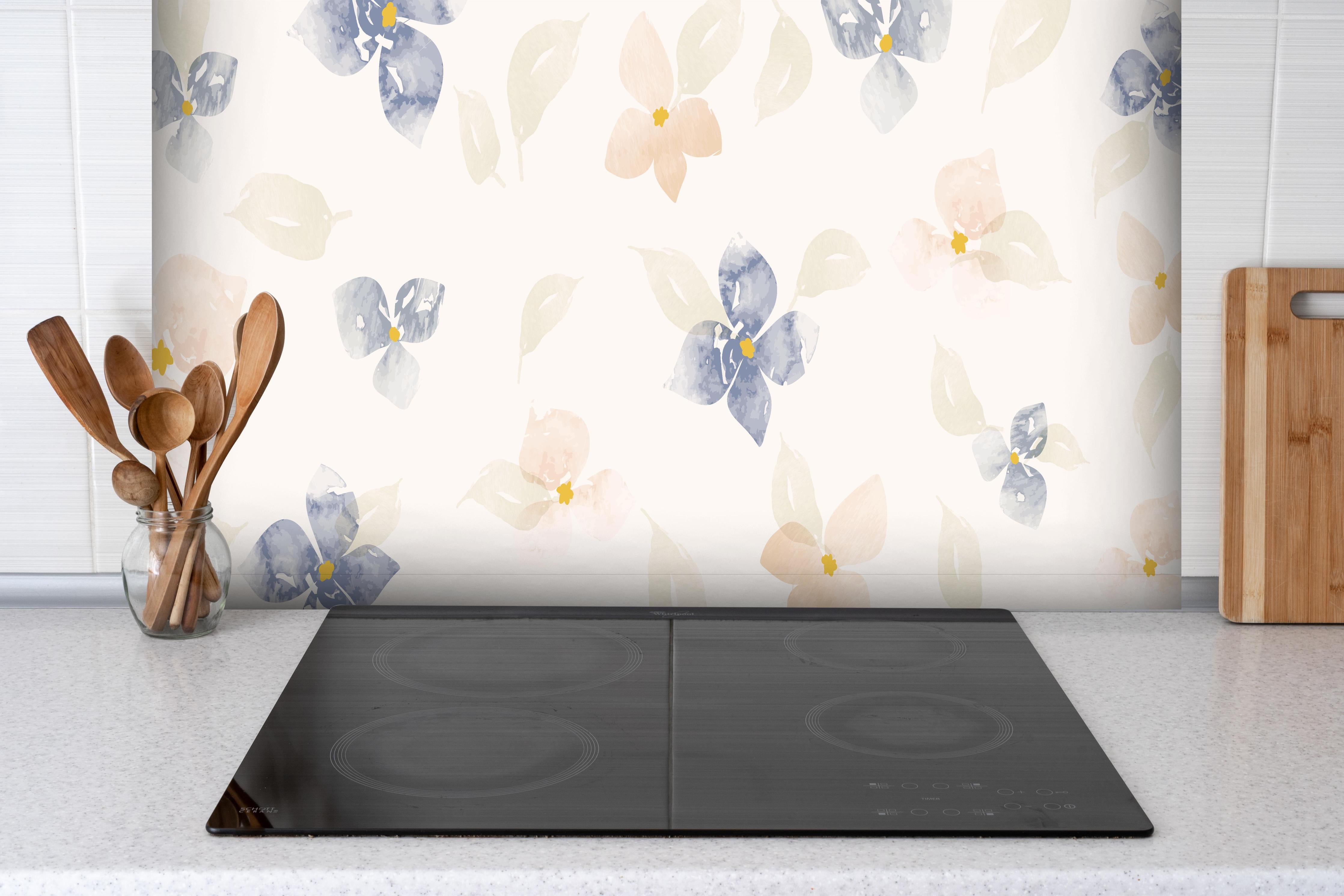 Spritzschutz - Zartes Blumenmuster in Pastellfarben hinter einem Cerankochfeld zwischen Holz-Kochutensilien