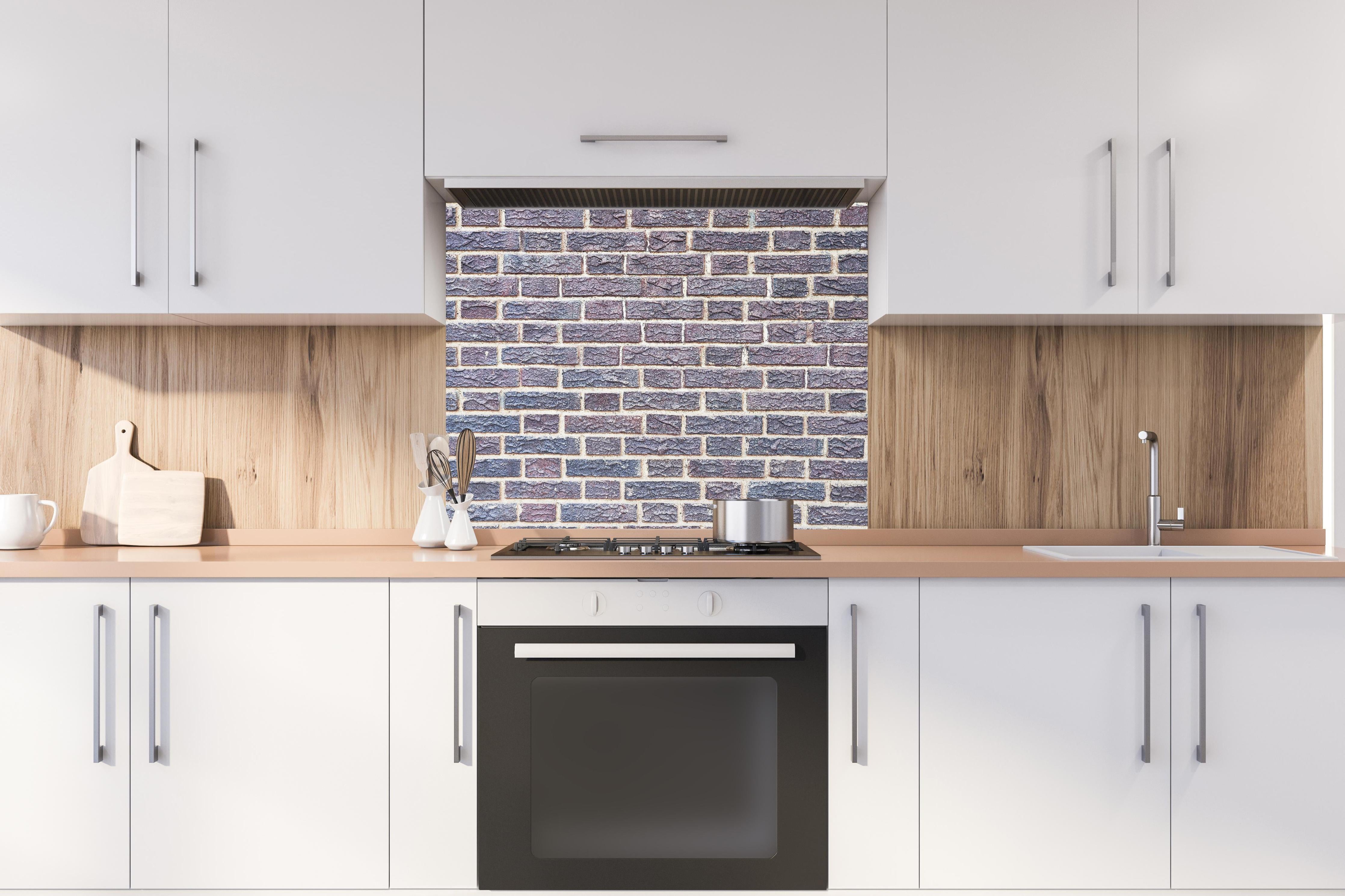 Spritzschutz - Zementmauertextur mit rissigen Fliesen hinter einem Cerankochfeld zwischen Holz-Kochutensilien