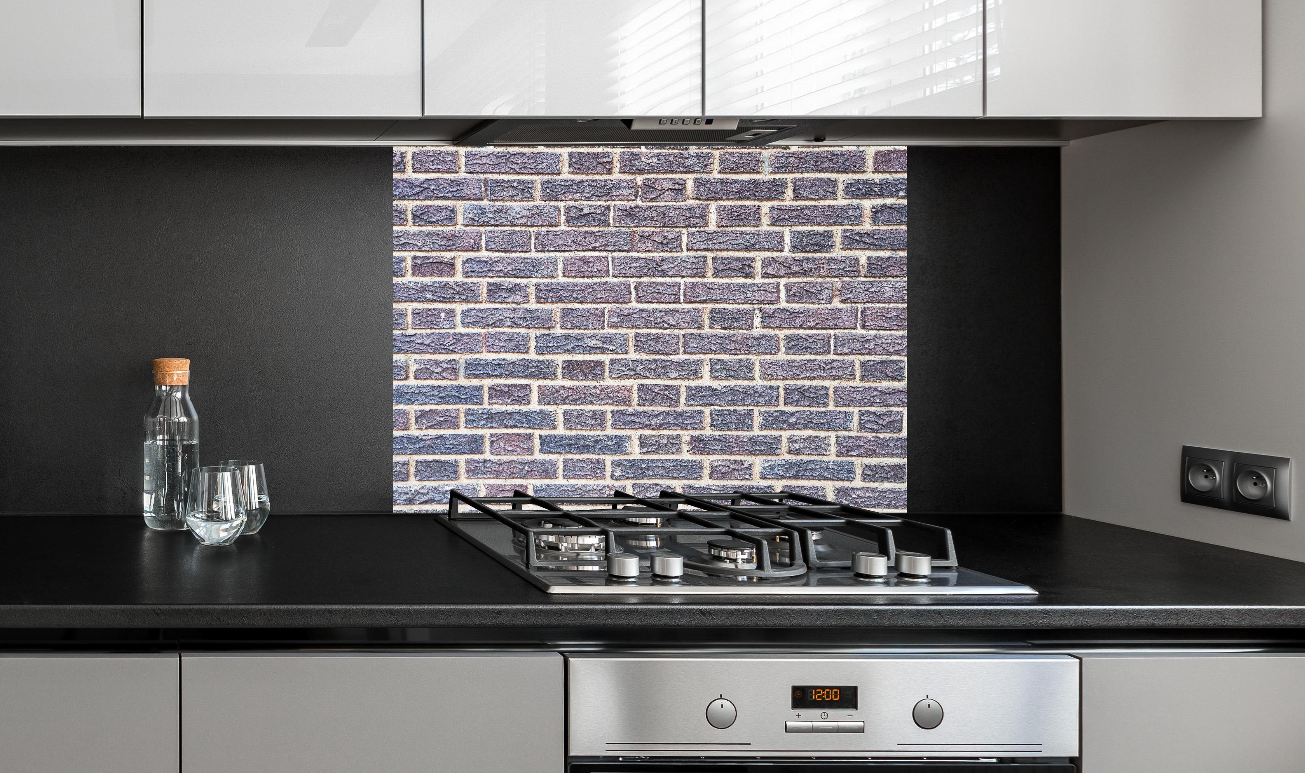 Spritzschutz - Zementmauertextur mit rissigen Fliesen hinter einem Cerankochfeld zwischen Holz-Kochutensilien