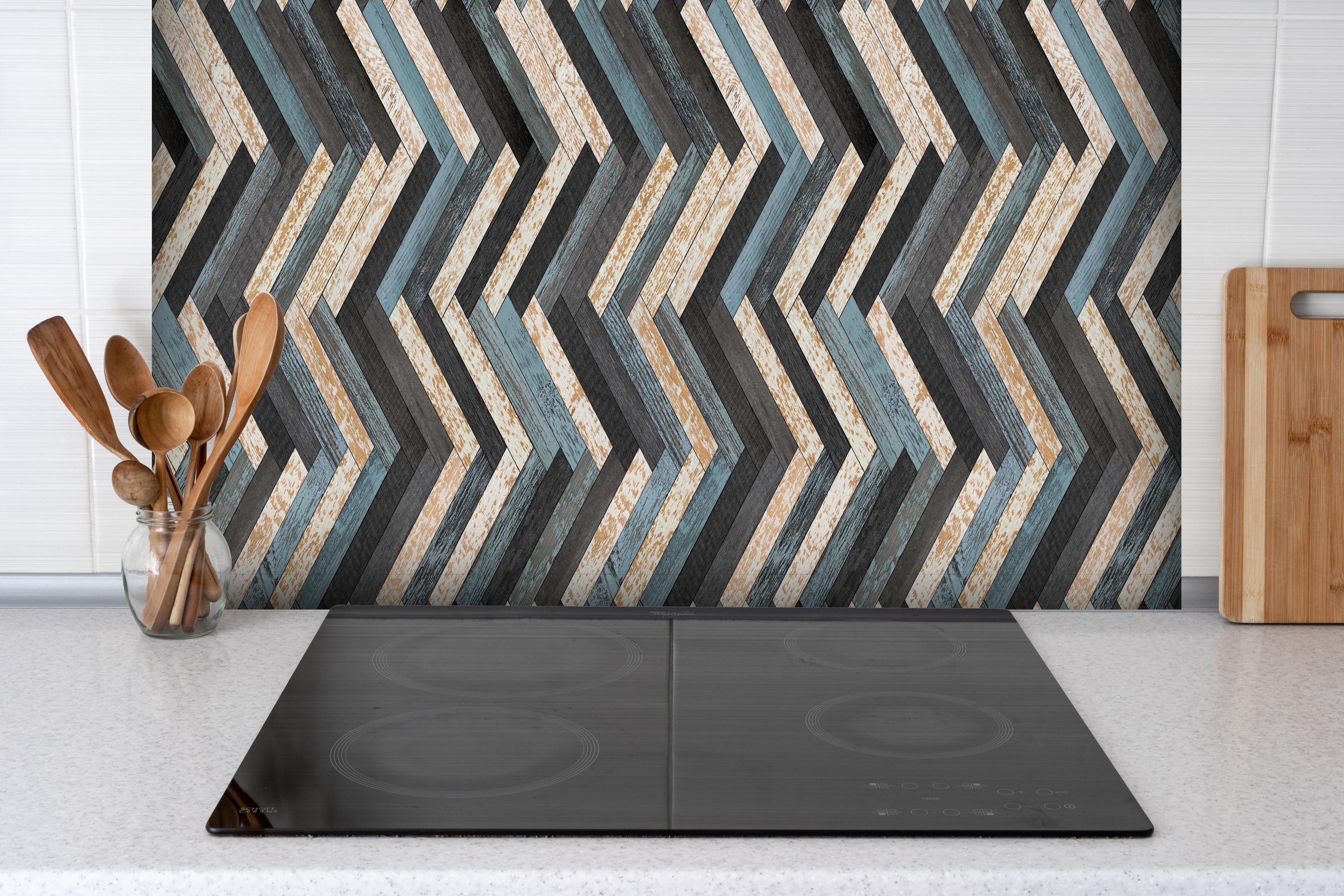 Spritzschutz - Zickzackförmige Holztextur hinter einem Cerankochfeld zwischen Holz-Kochutensilien