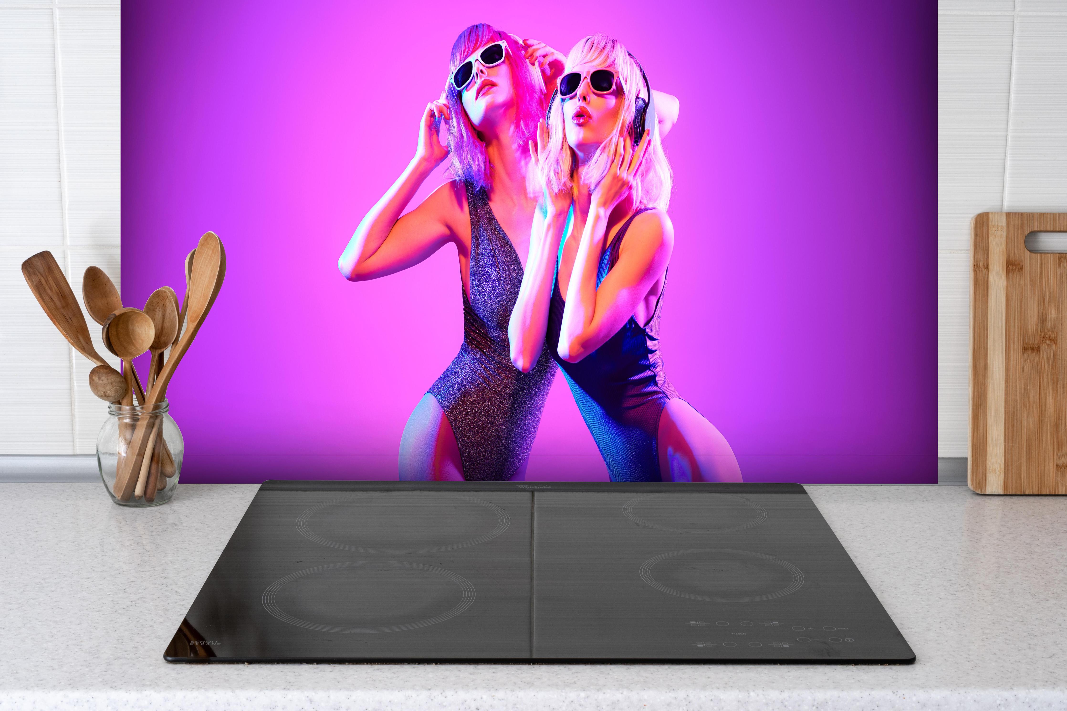 Spritzschutz - Zwei DJ Fitness Frau in bunten Neonlicht. Disco hinter einem Cerankochfeld zwischen Holz-Kochutensilien