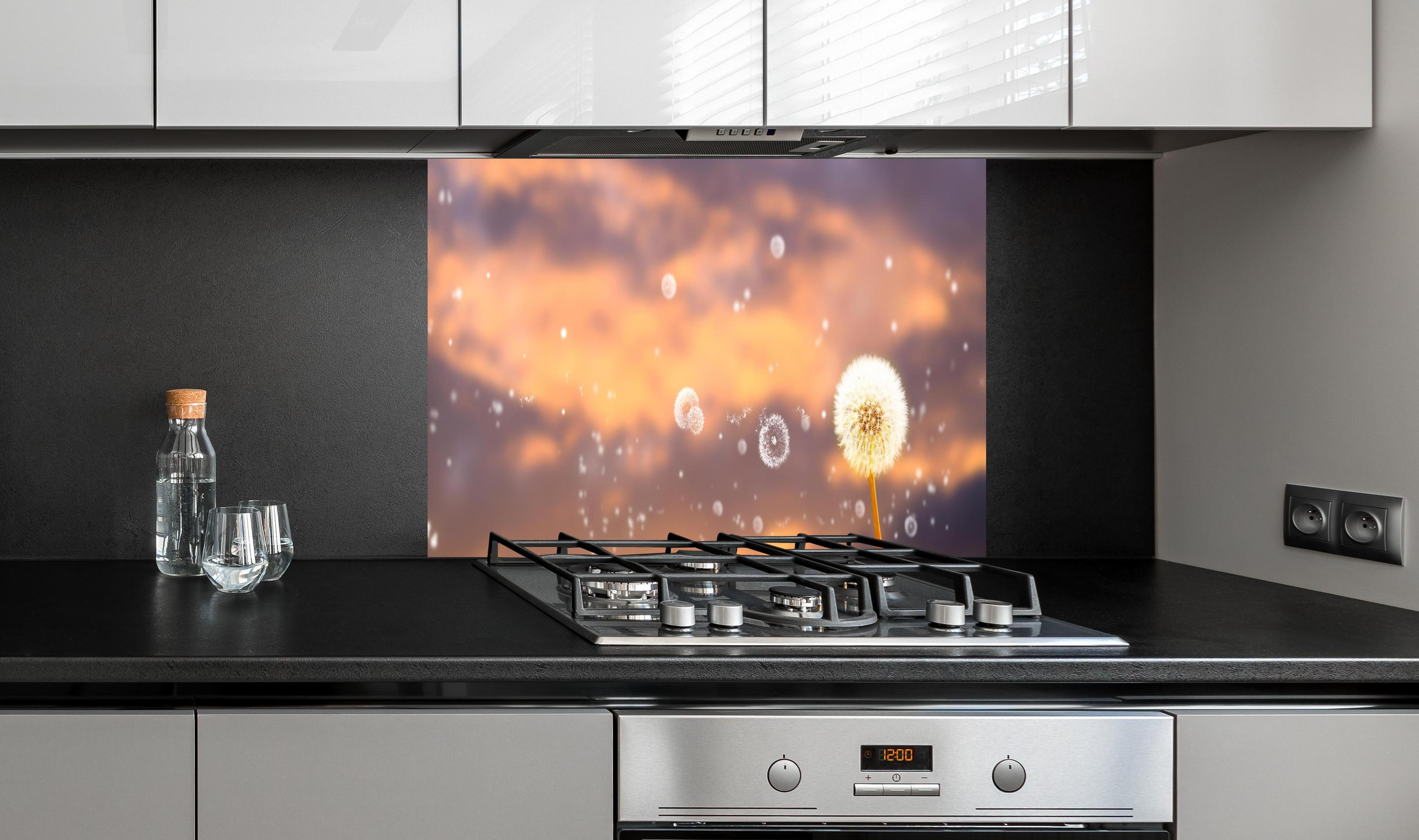 Spritzschutz - blütenstaub von pusteblumen in der abendsonne hinter einem Cerankochfeld zwischen Holz-Kochutensilien