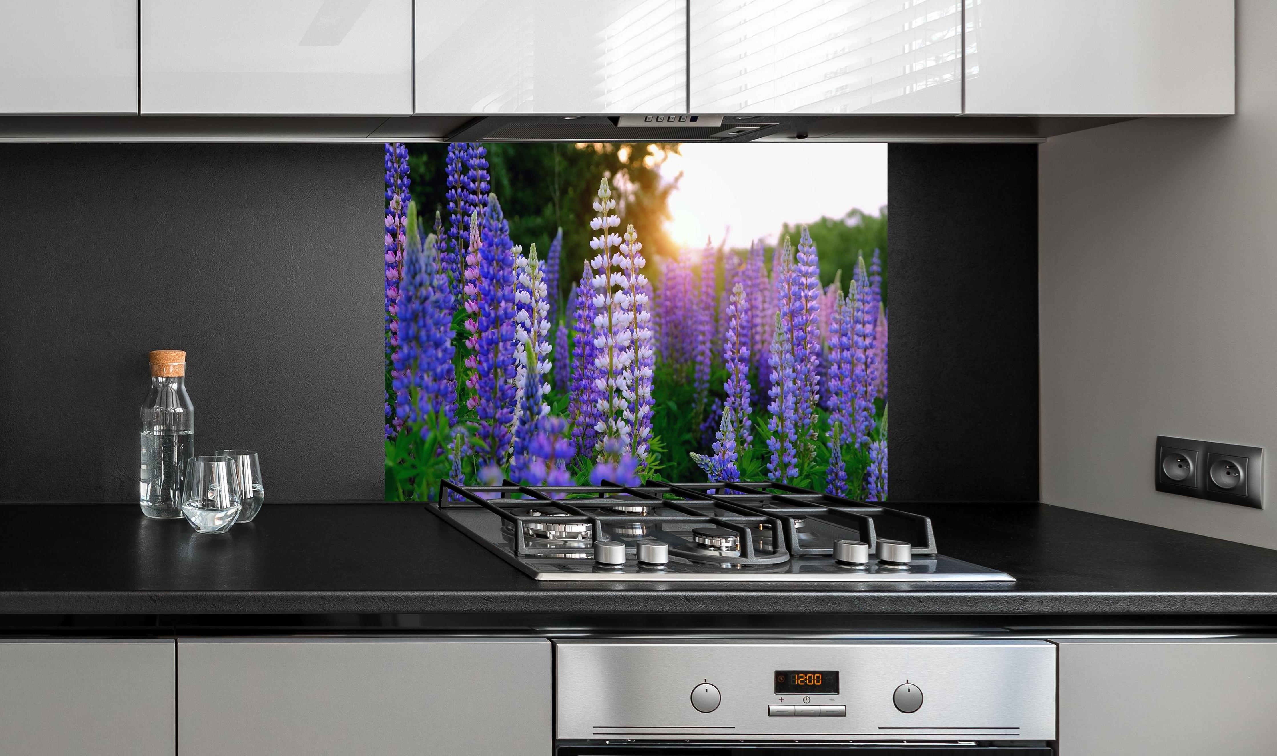 Spritzschutz - lila-rosa Lupine Blumen hinter einem Cerankochfeld zwischen Holz-Kochutensilien