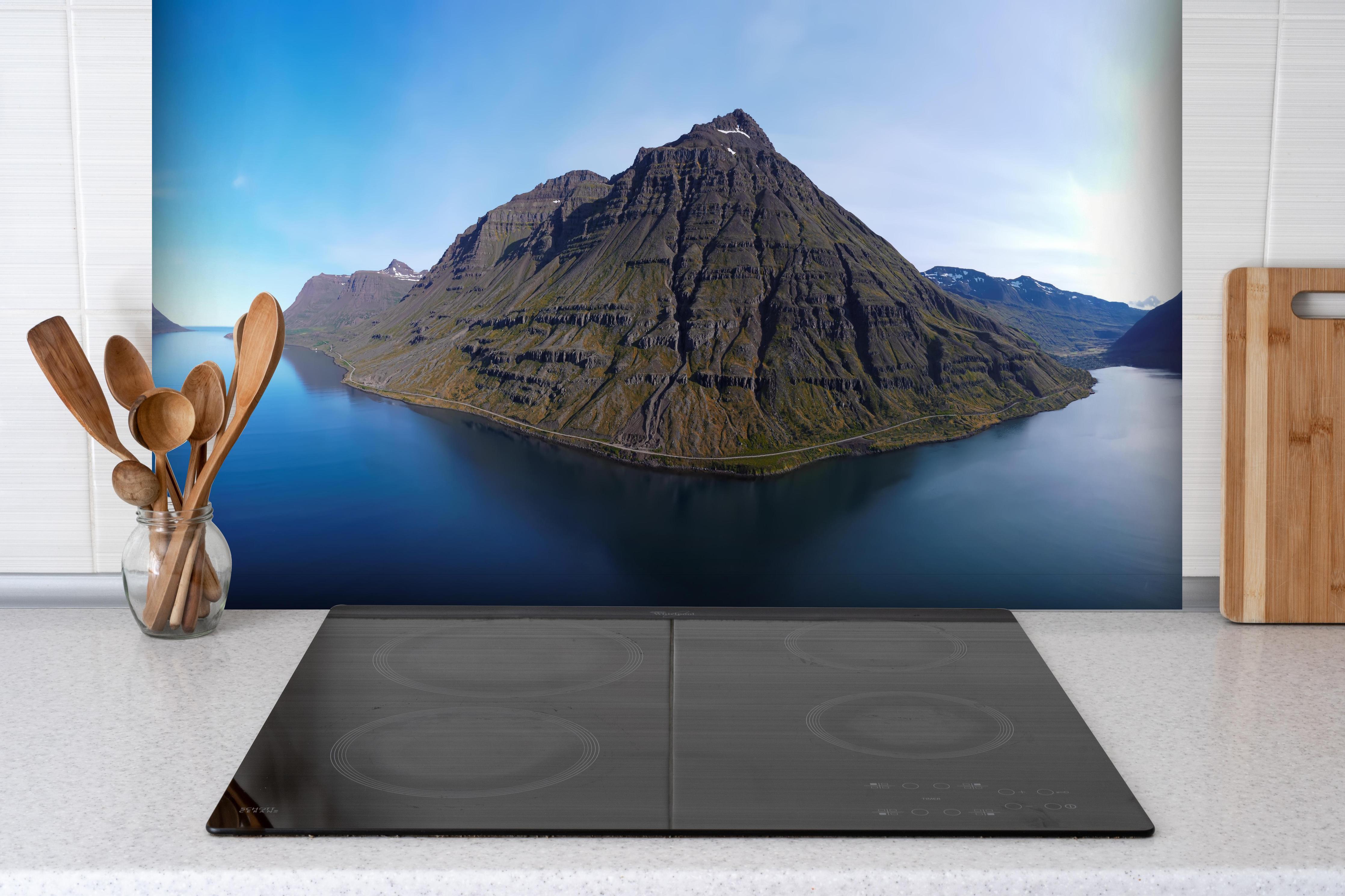 Spritzschutz - luftbildpanorama in den isländischen ostfjorden hinter einem Cerankochfeld zwischen Holz-Kochutensilien