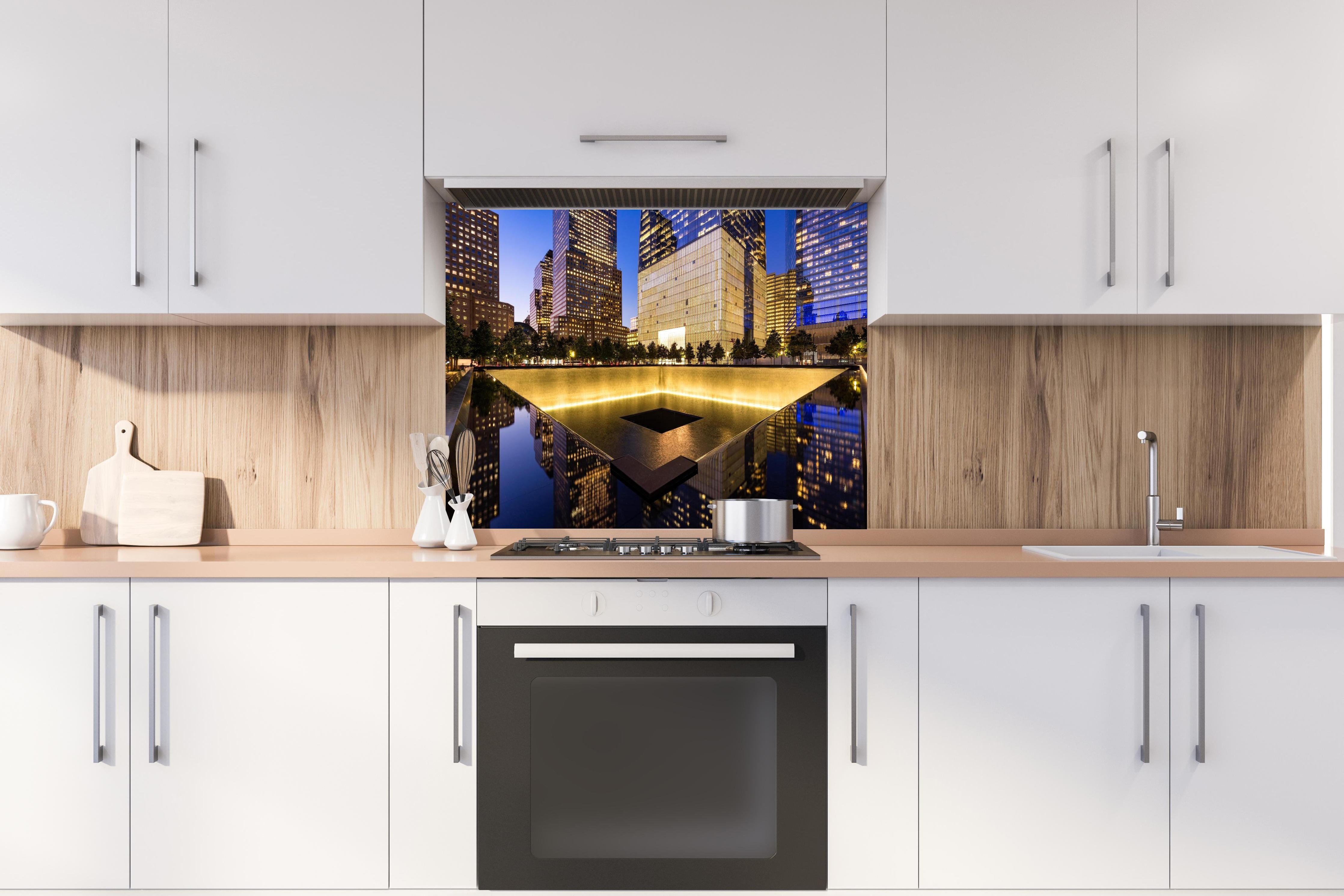 Spritzschutz - nächtlich Beleuchtetes World Trade Center Site hinter einem Cerankochfeld zwischen Holz-Kochutensilien