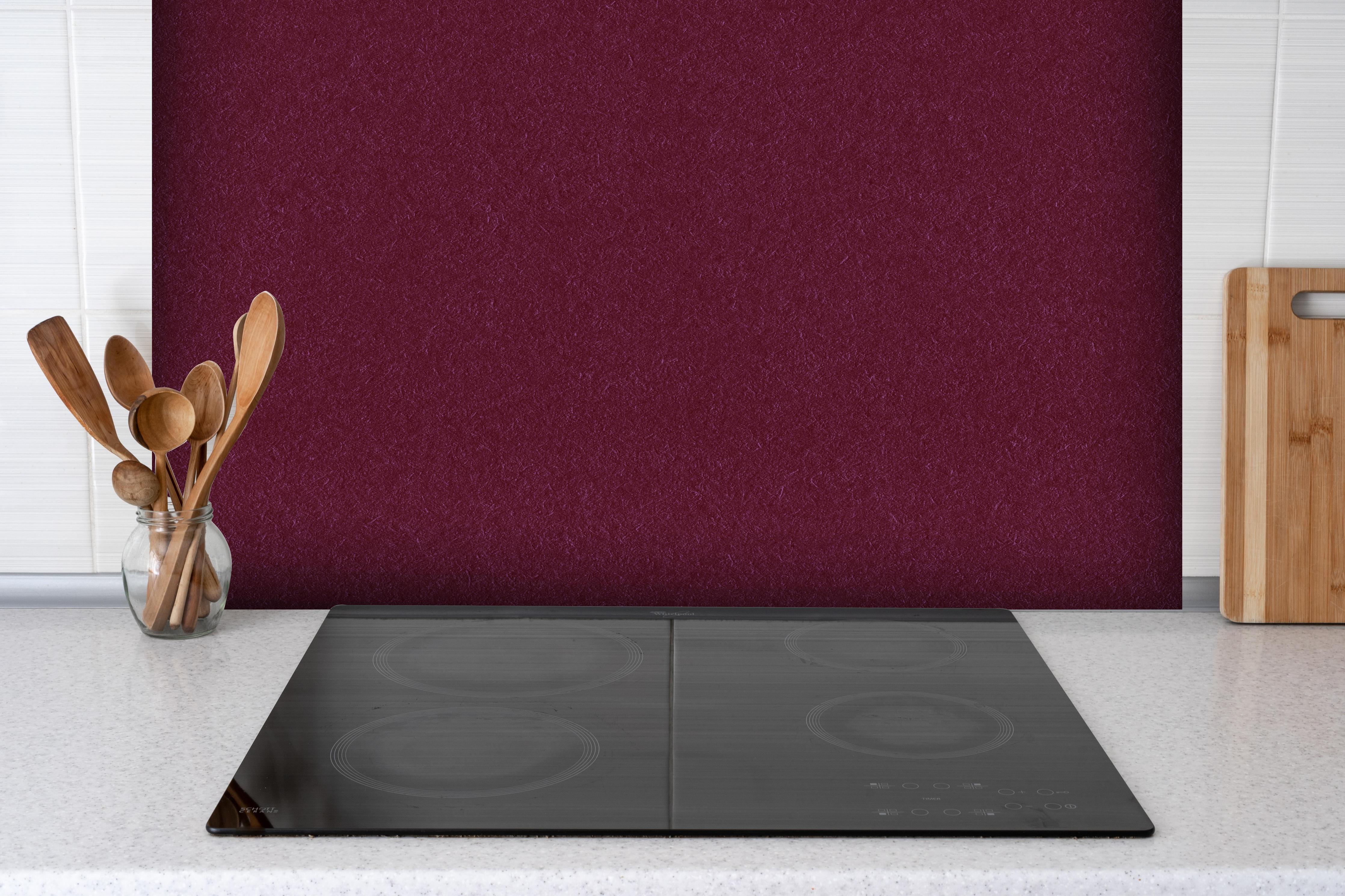 Spritzschutz - traditionelle rötliches Papier hinter einem Cerankochfeld zwischen Holz-Kochutensilien