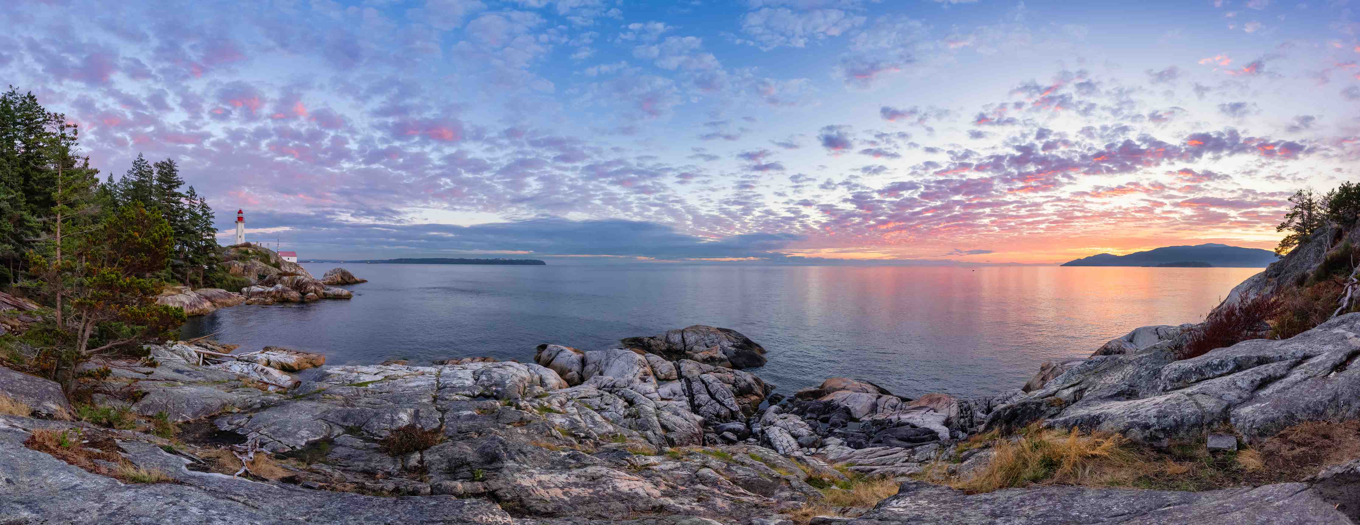 Wandverkleidung Bad-Blick auf den Sonnenuntergang über einem See mit Felsen und Bäumen