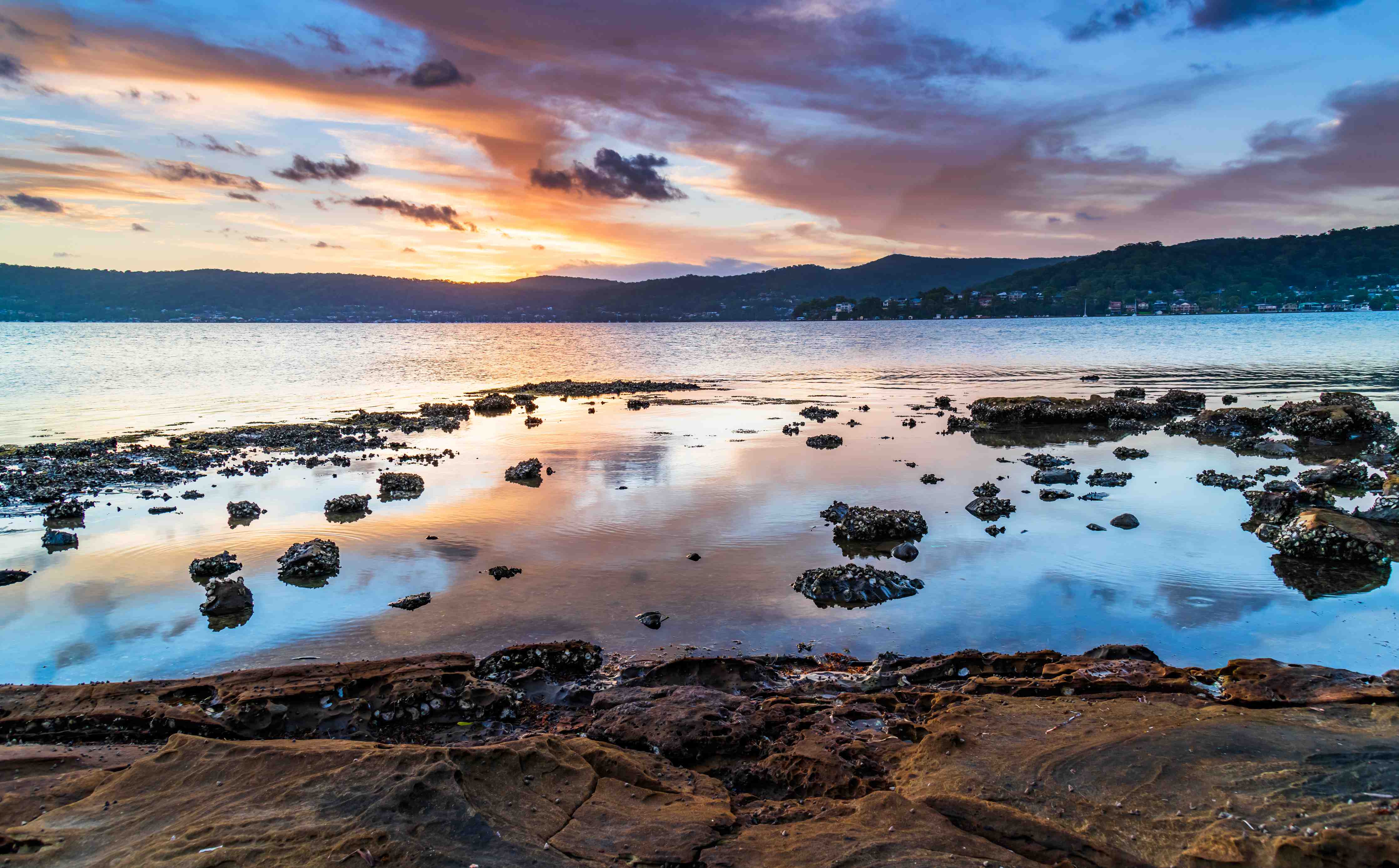 Wandverkleidung Bad-Sonnenuntergang über dem See mit Felsen und Bergen