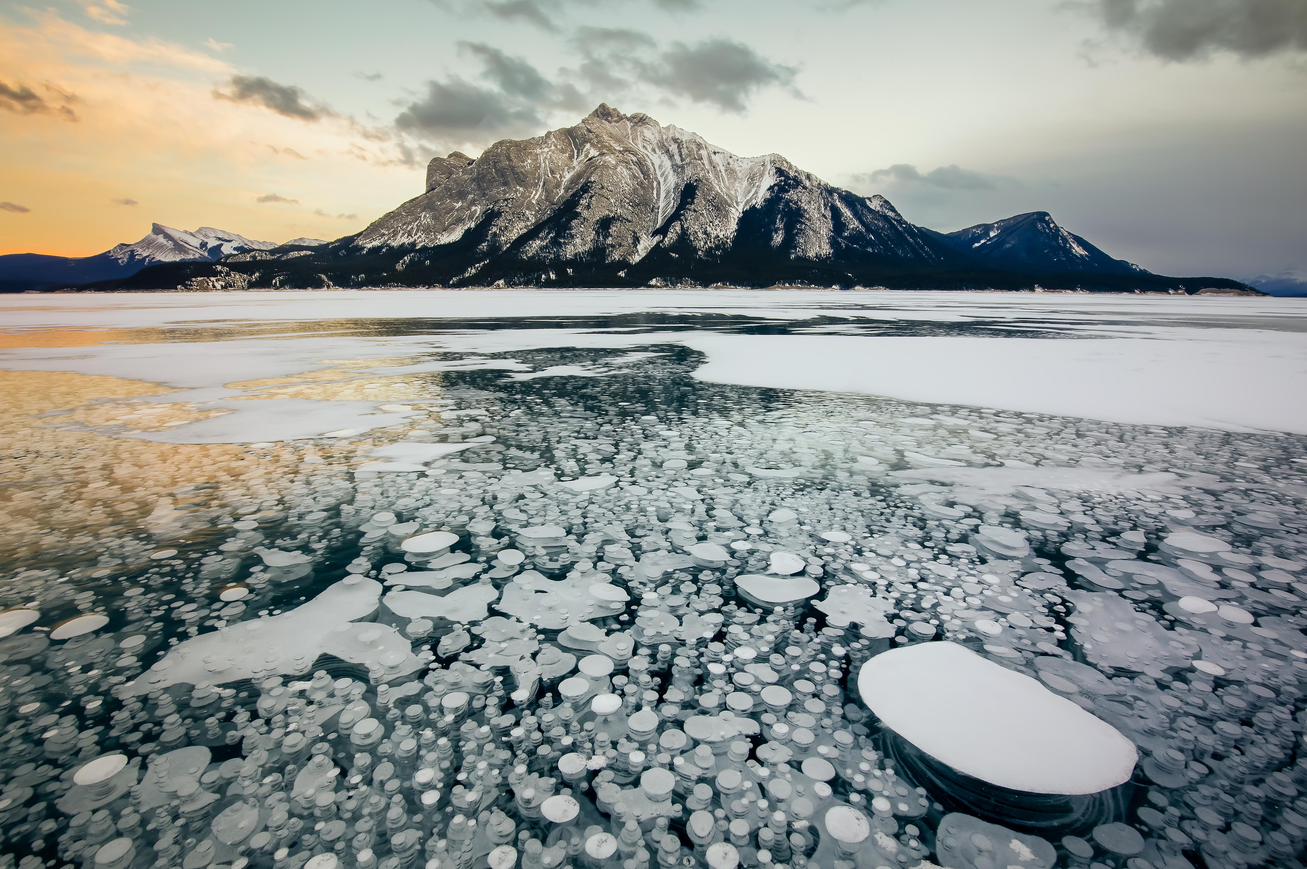 Duschrückwand-Eisblasen im gefrorenen Bergsee bei Sonnenuntergang