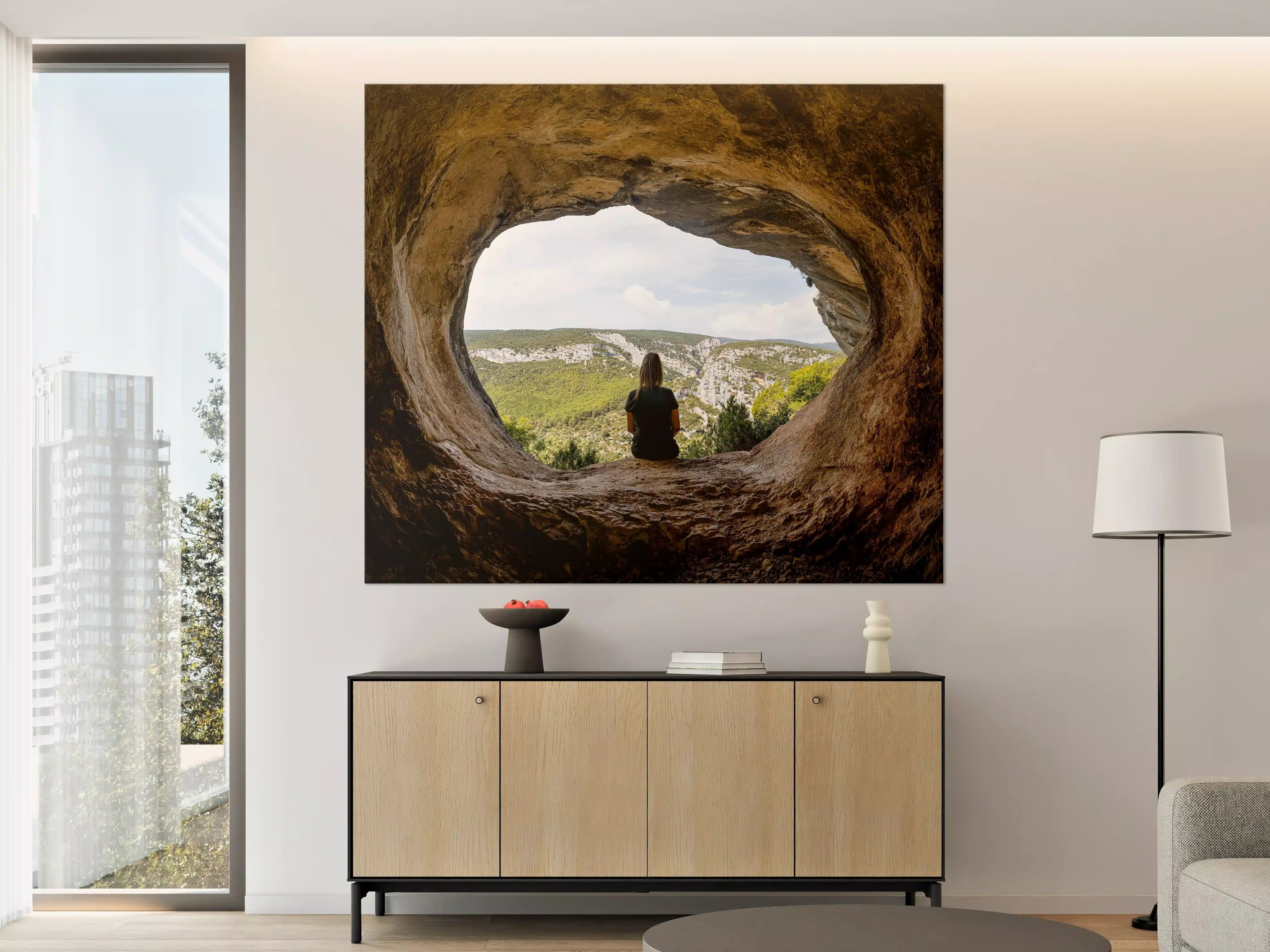 Große Wandbilder - Frau sitzend in Berghöhle mit Blick auf Landschaft