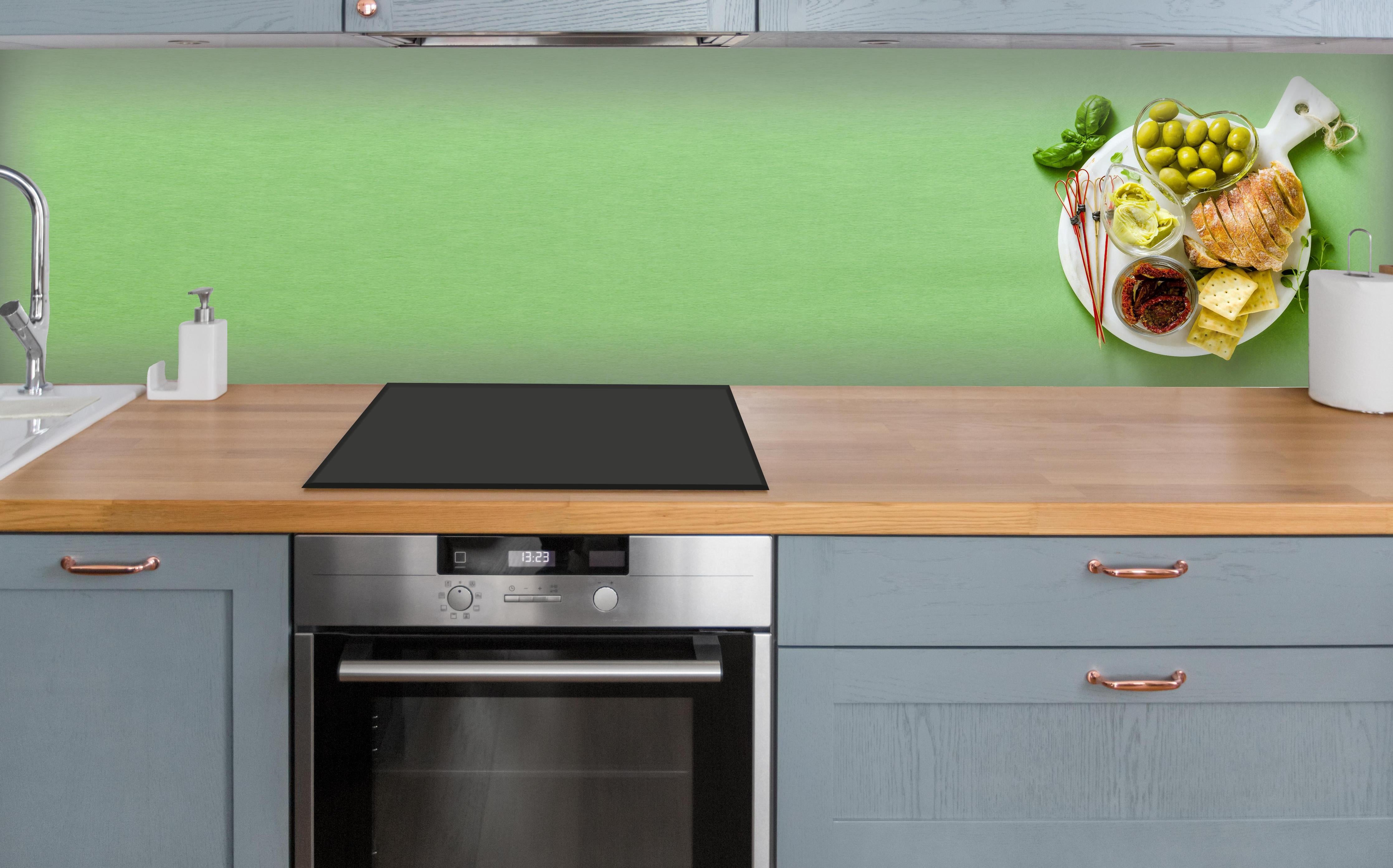 Küche - Grüne Küchenrückwand mit Oliven über polierter Holzarbeitsplatte mit Cerankochfeld