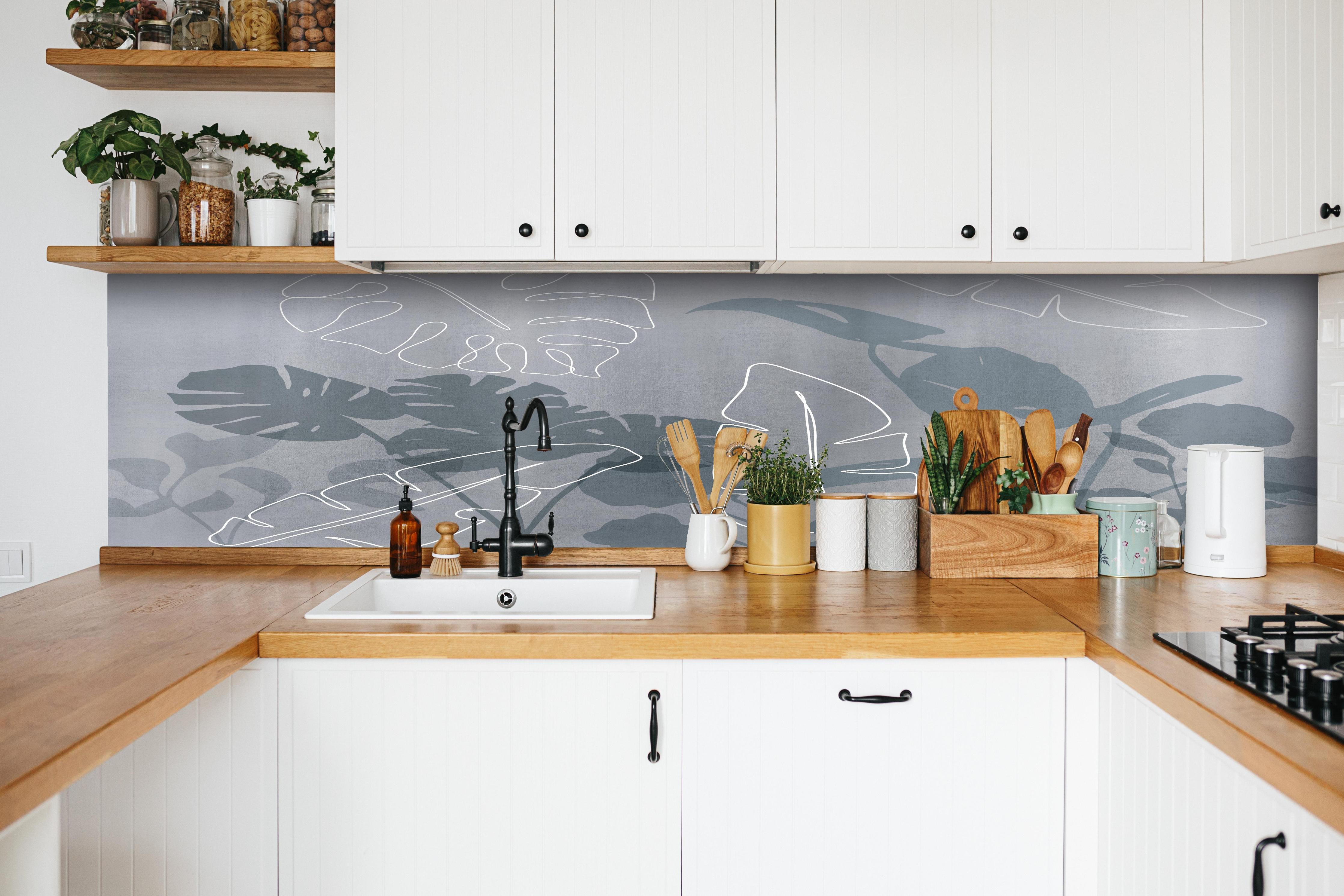 Küche - Abstrakte Blätter hinter weißen Hochglanz-Küchenregalen und schwarzem Wasserhahn