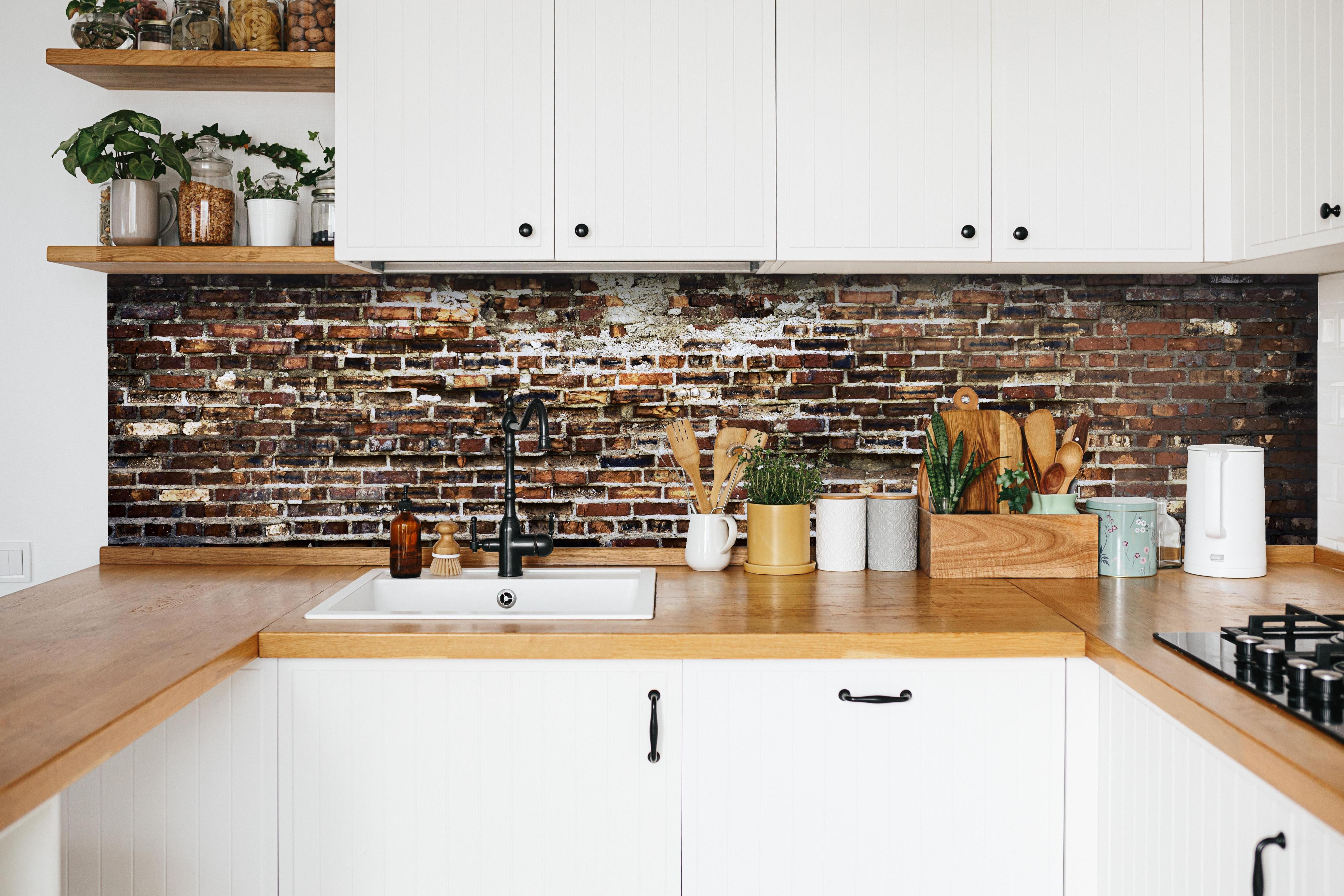 Küche - Alte Rote Ziegelwand mit Verputz hinter weißen Hochglanz-Küchenregalen und schwarzem Wasserhahn