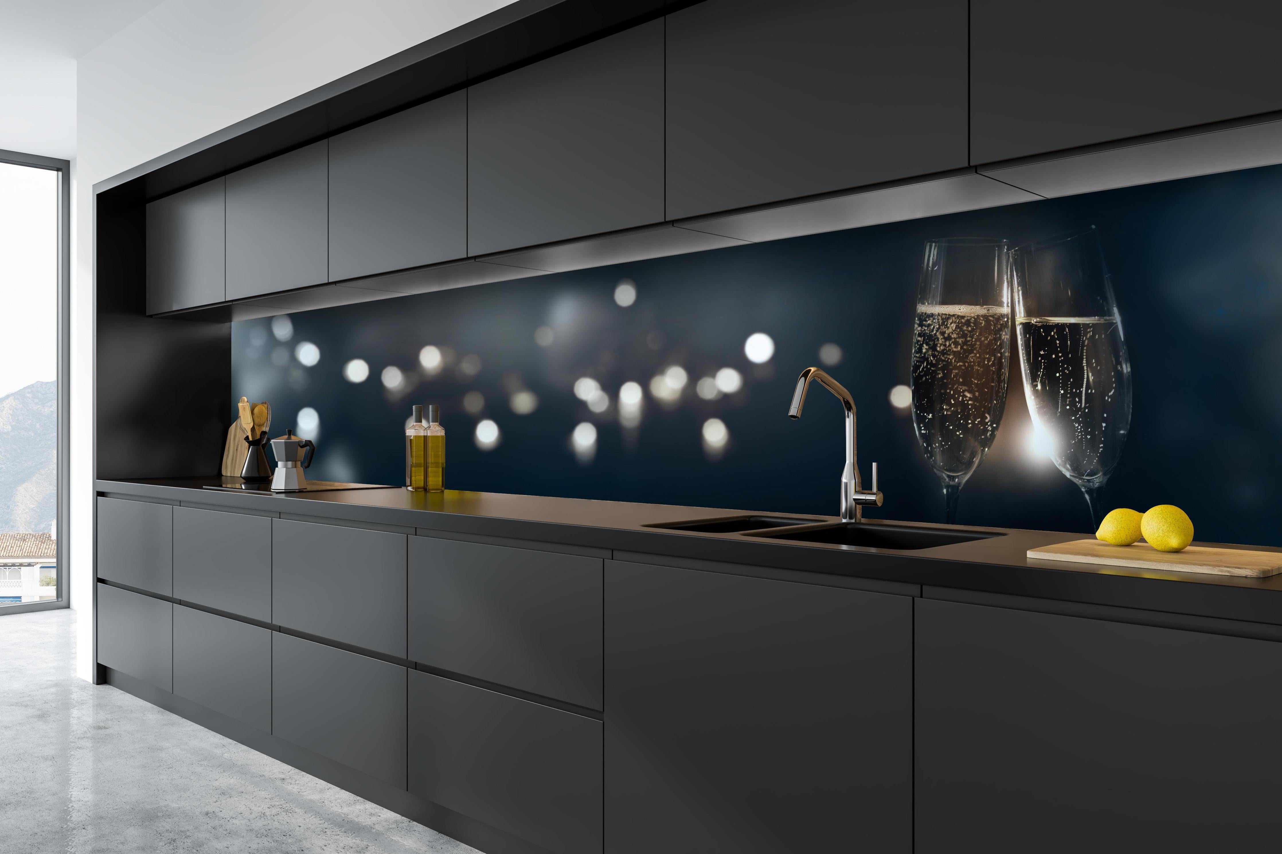 Küche - Anstoßen mit funkelndem Champagner hinter weißen Hochglanz-Küchenregalen und schwarzem Wasserhahn