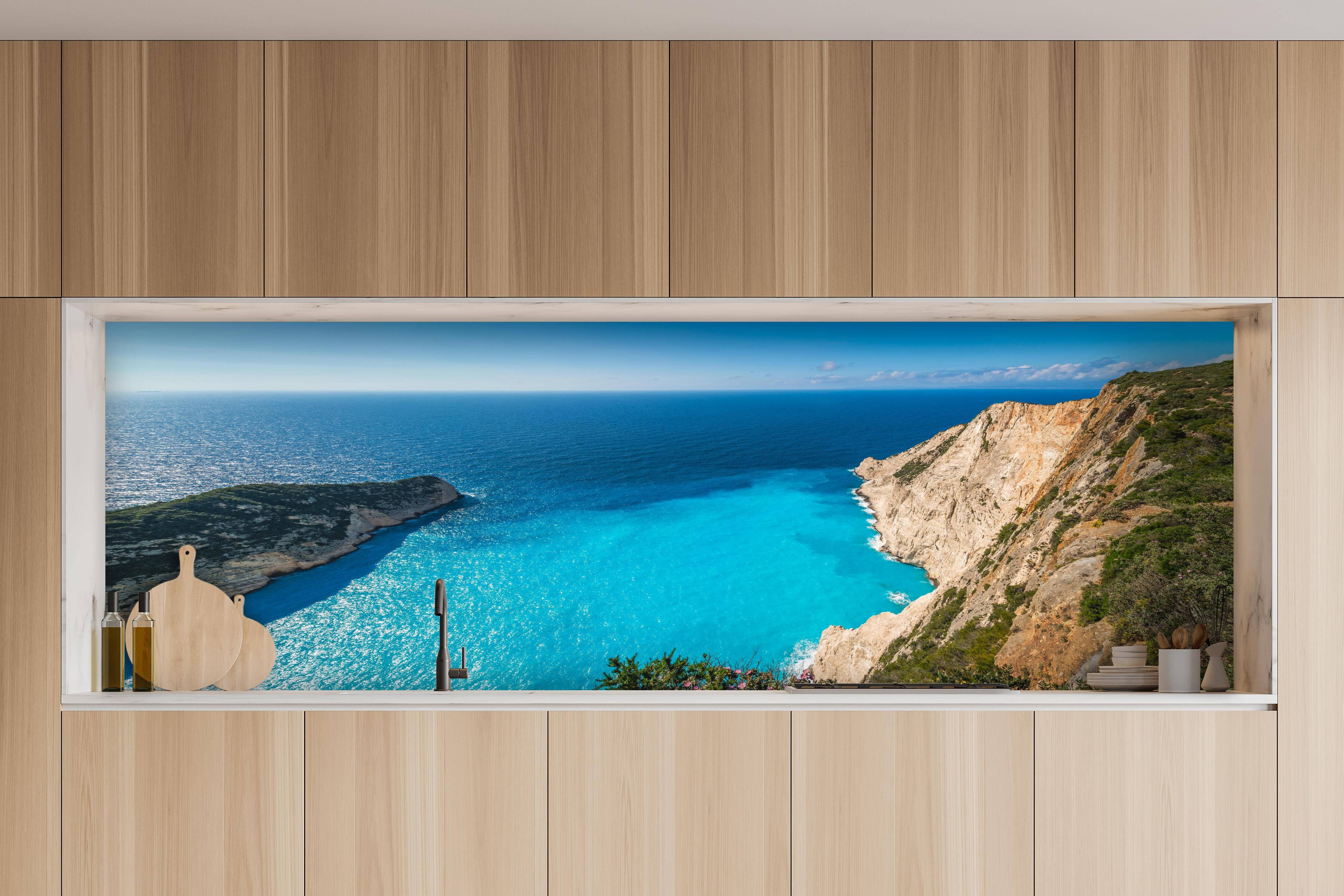 Küche - Atemberaubende Aussicht auf türkisblaue Küstenlandschaft hinter weißen Hochglanz-Küchenregalen und schwarzem Wasserhahn