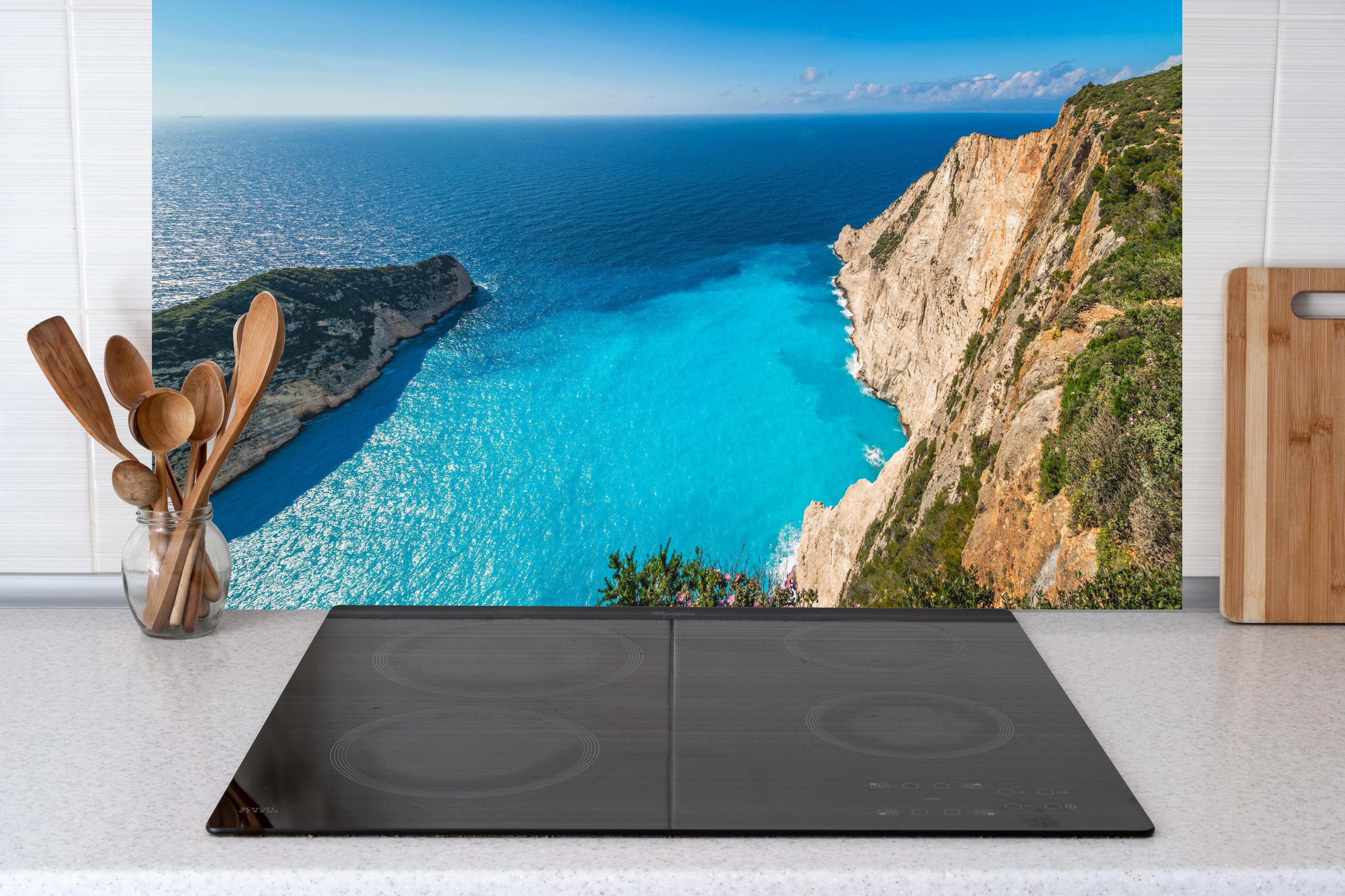 Küche - Atemberaubende Aussicht auf türkisblaue Küstenlandschaft hinter weißen Hochglanz-Küchenregalen und schwarzem Wasserhahn