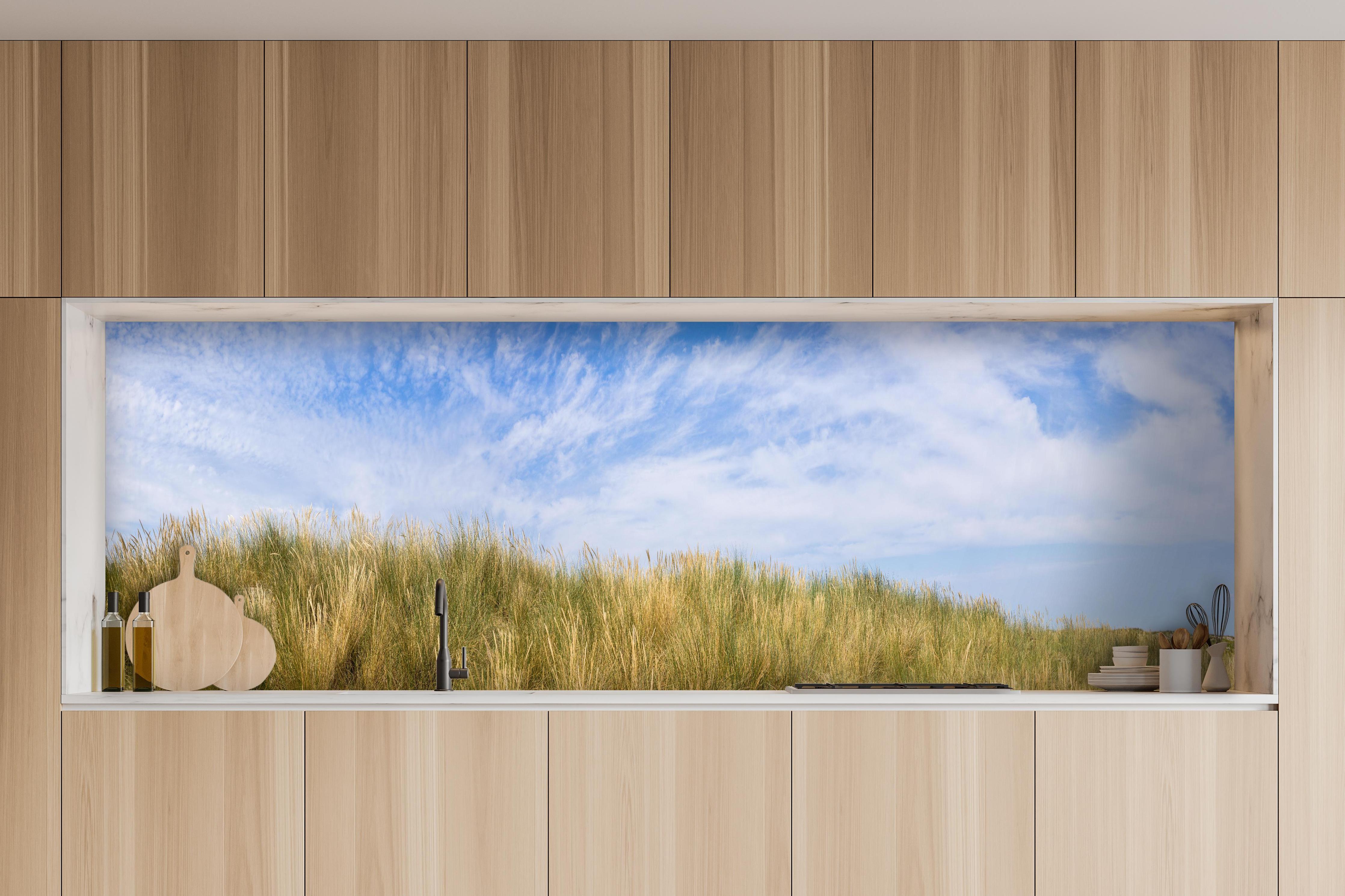 Küche - Atemberaubende Küstenlandschaft unter blauem Himmel hinter weißen Hochglanz-Küchenregalen und schwarzem Wasserhahn