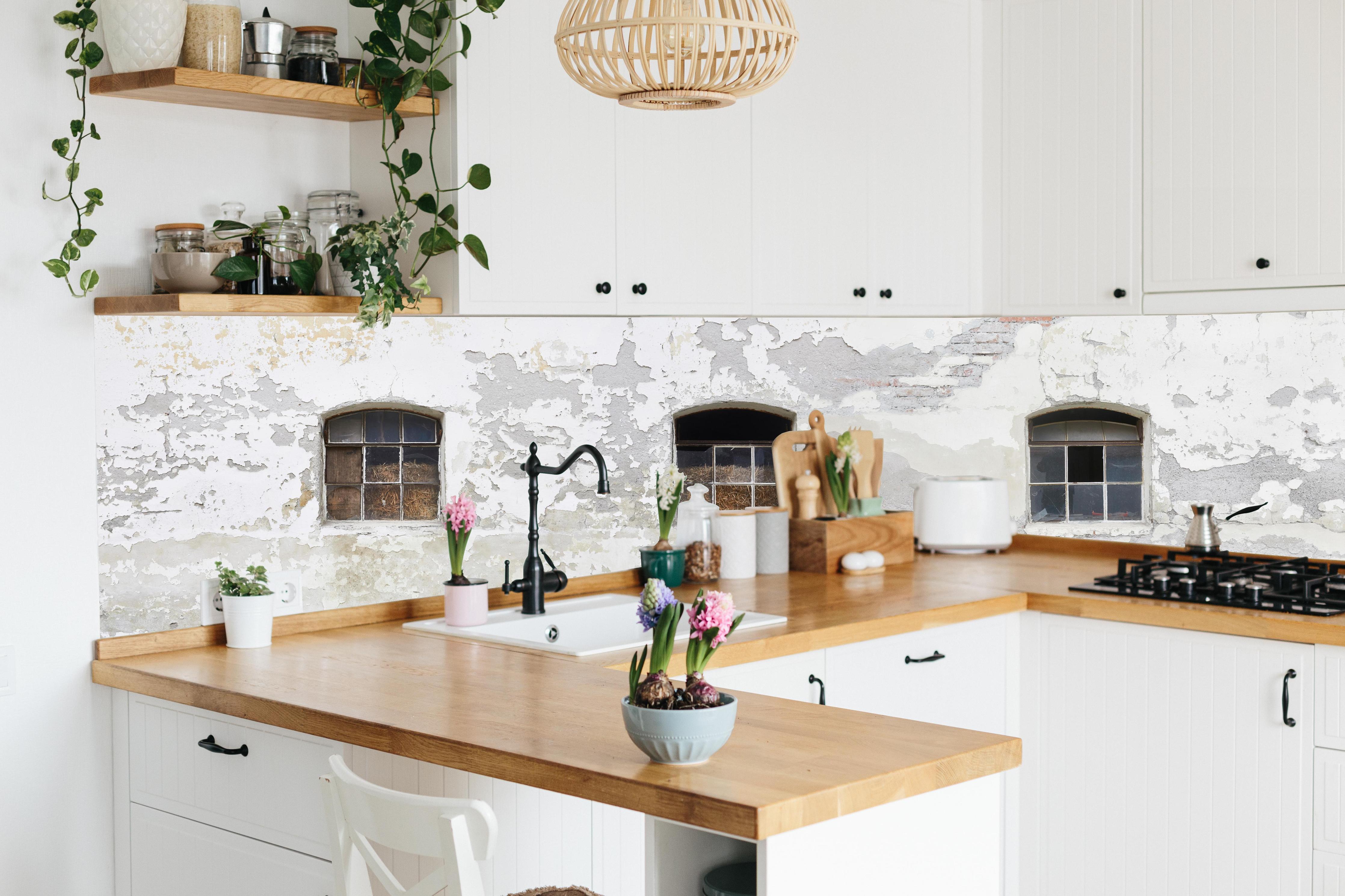 Küche - Beschädigte Fenster einer veralteten Hauswand hinter weißen Hochglanz-Küchenregalen und schwarzem Wasserhahn