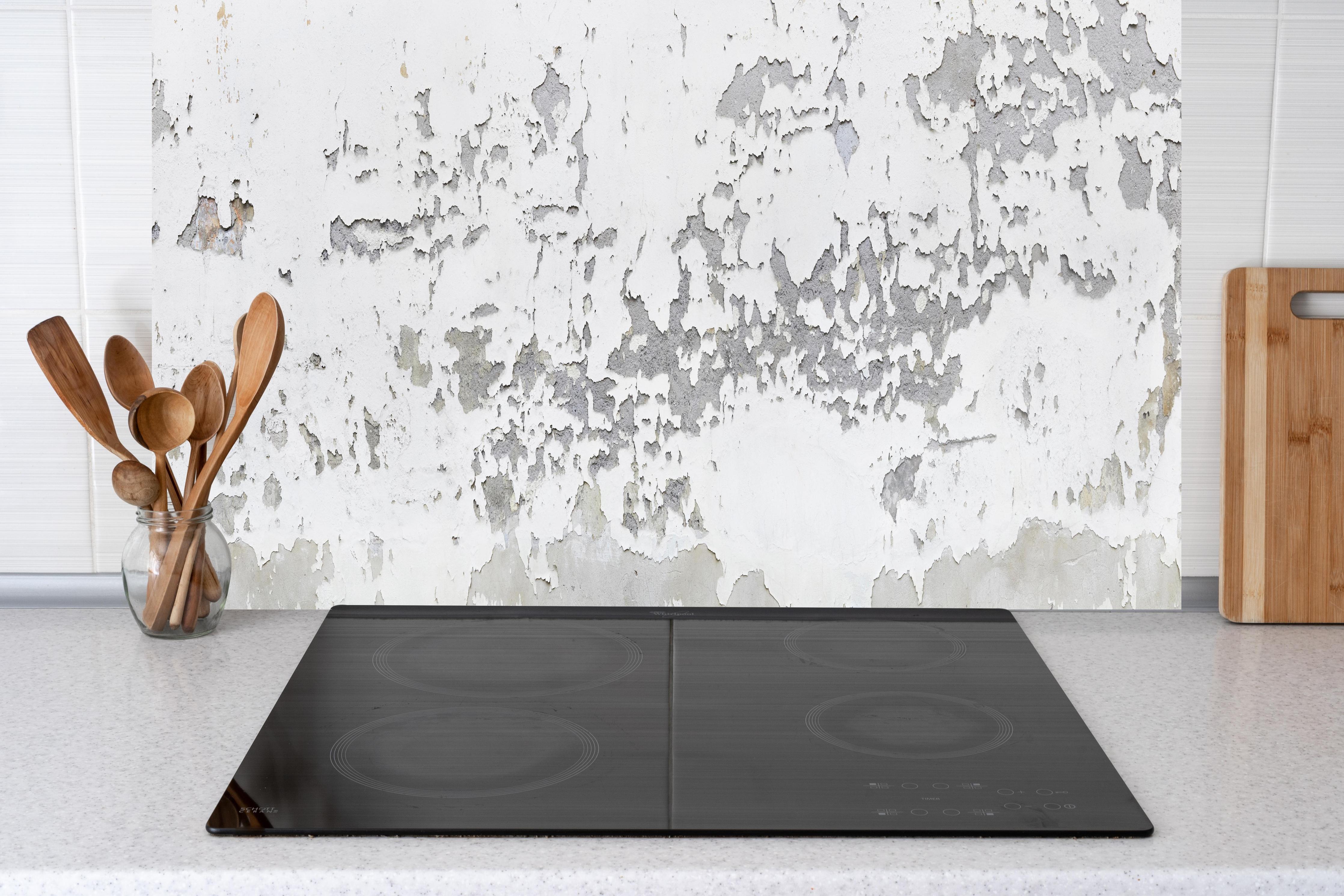 Küche - Beschädigte Wandstruktur hinter weißen Hochglanz-Küchenregalen und schwarzem Wasserhahn