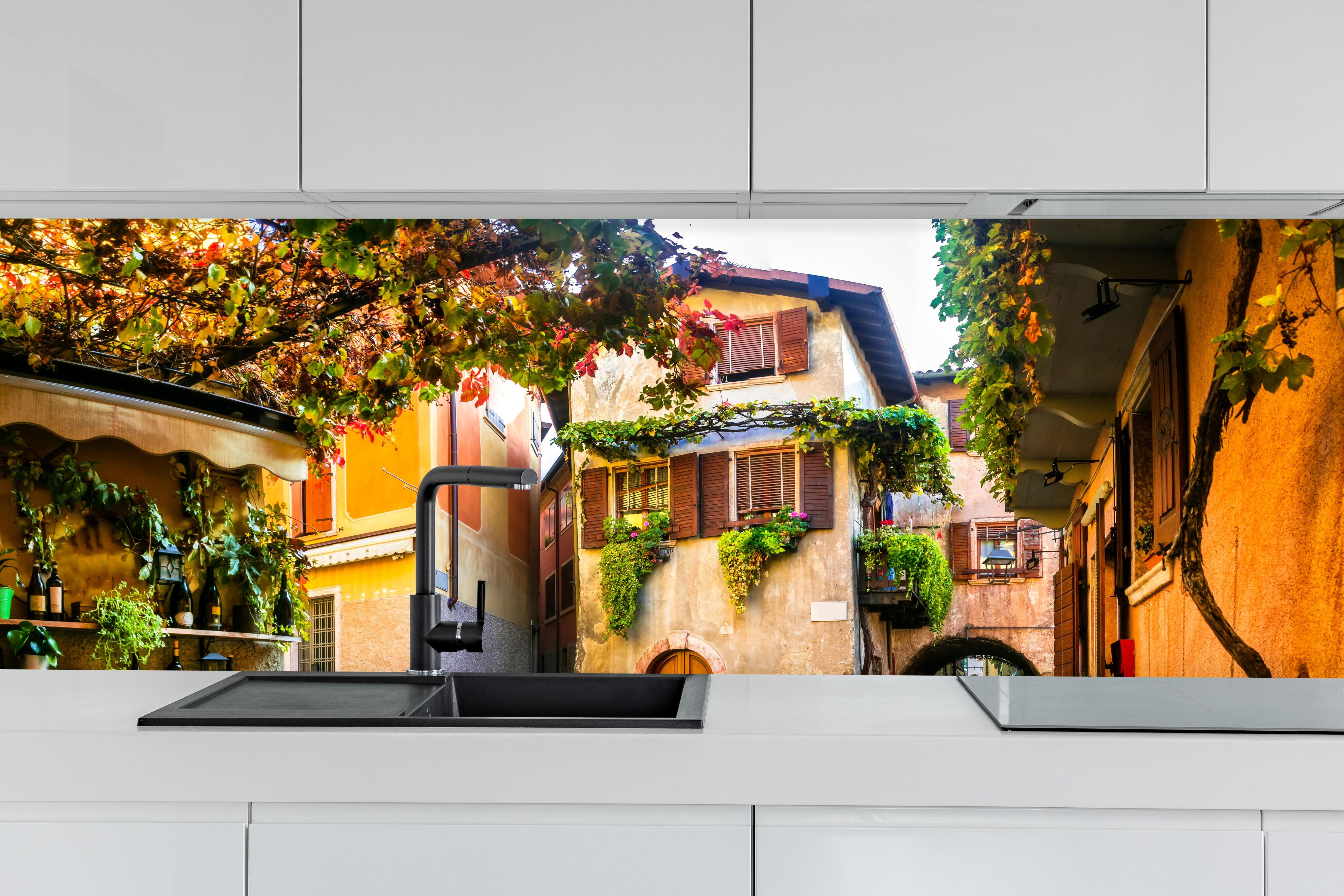 Küche - Bezaubernde alte Gasse in Malcesine hinter weißen Hochglanz-Küchenregalen und schwarzem Wasserhahn