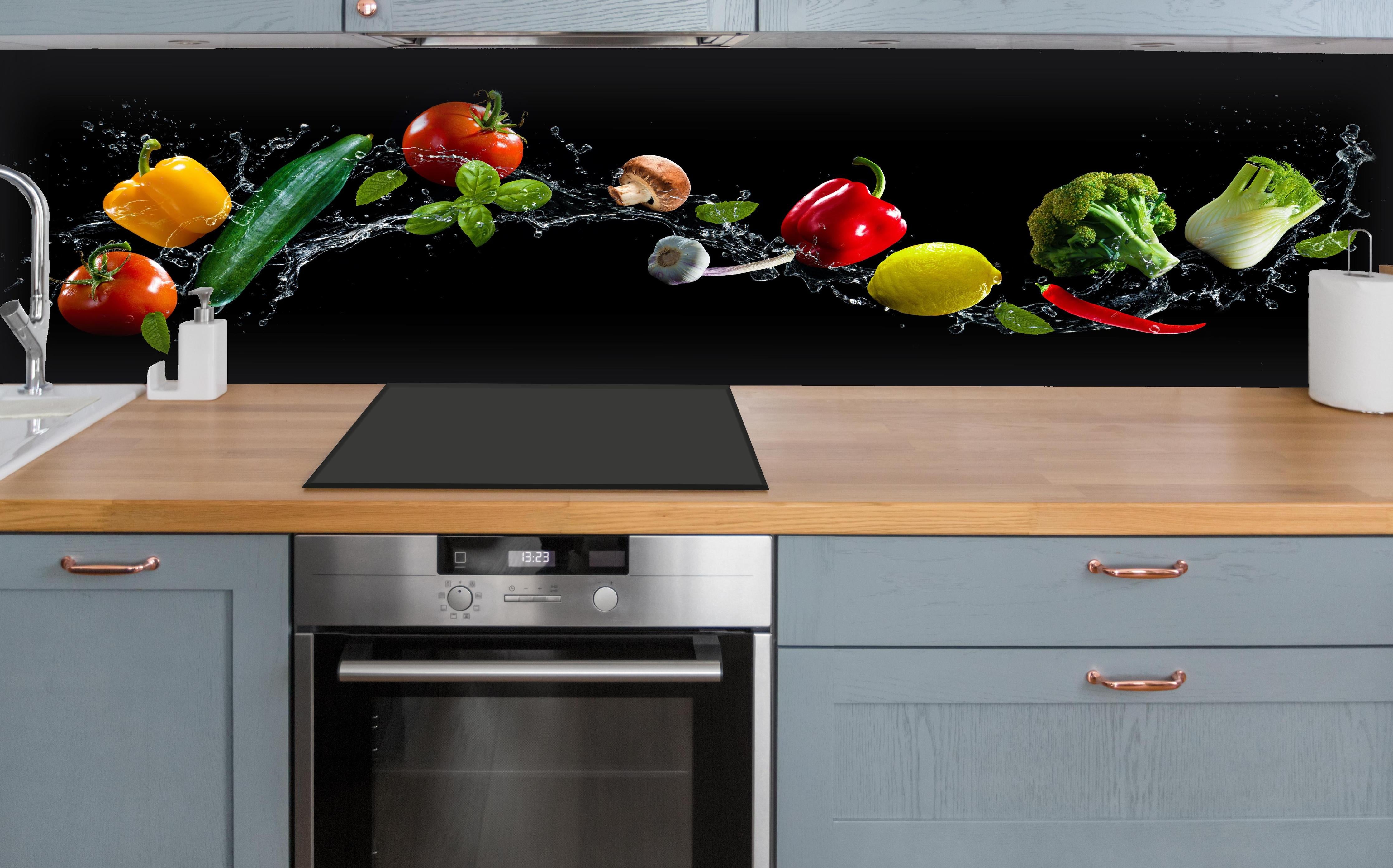 Küche - Buntes Spritzwasser-Gemüse auf Schwarz hinter weißen Hochglanz-Küchenregalen und schwarzem Wasserhahn