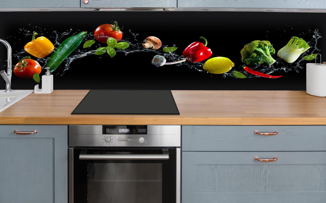 Küche - Buntes Spritzwasser-Gemüse auf Schwarz hinter weißen Hochglanz-Küchenregalen und schwarzem Wasserhahn