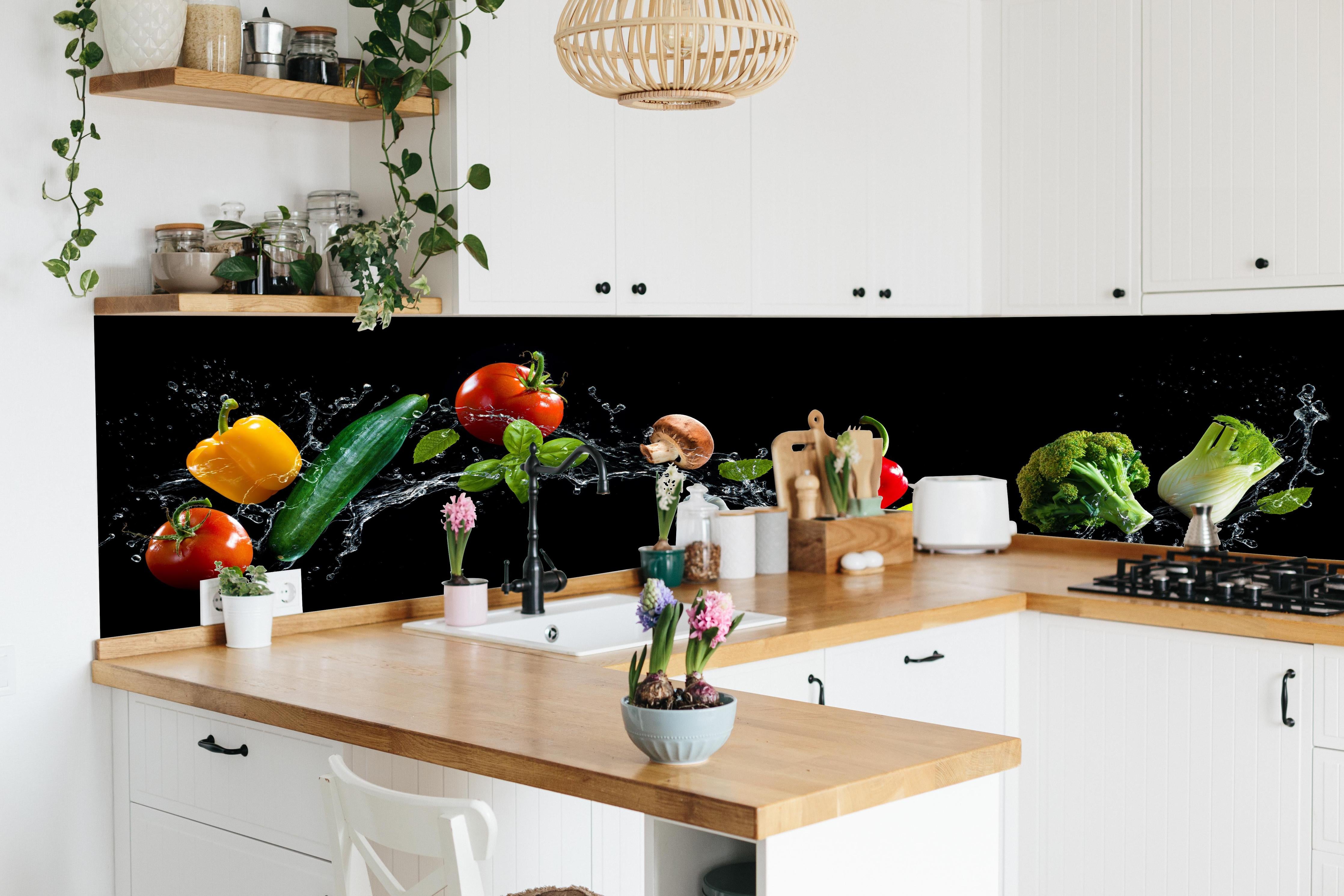 Küche - Buntes Spritzwasser-Gemüse auf Schwarz hinter weißen Hochglanz-Küchenregalen und schwarzem Wasserhahn