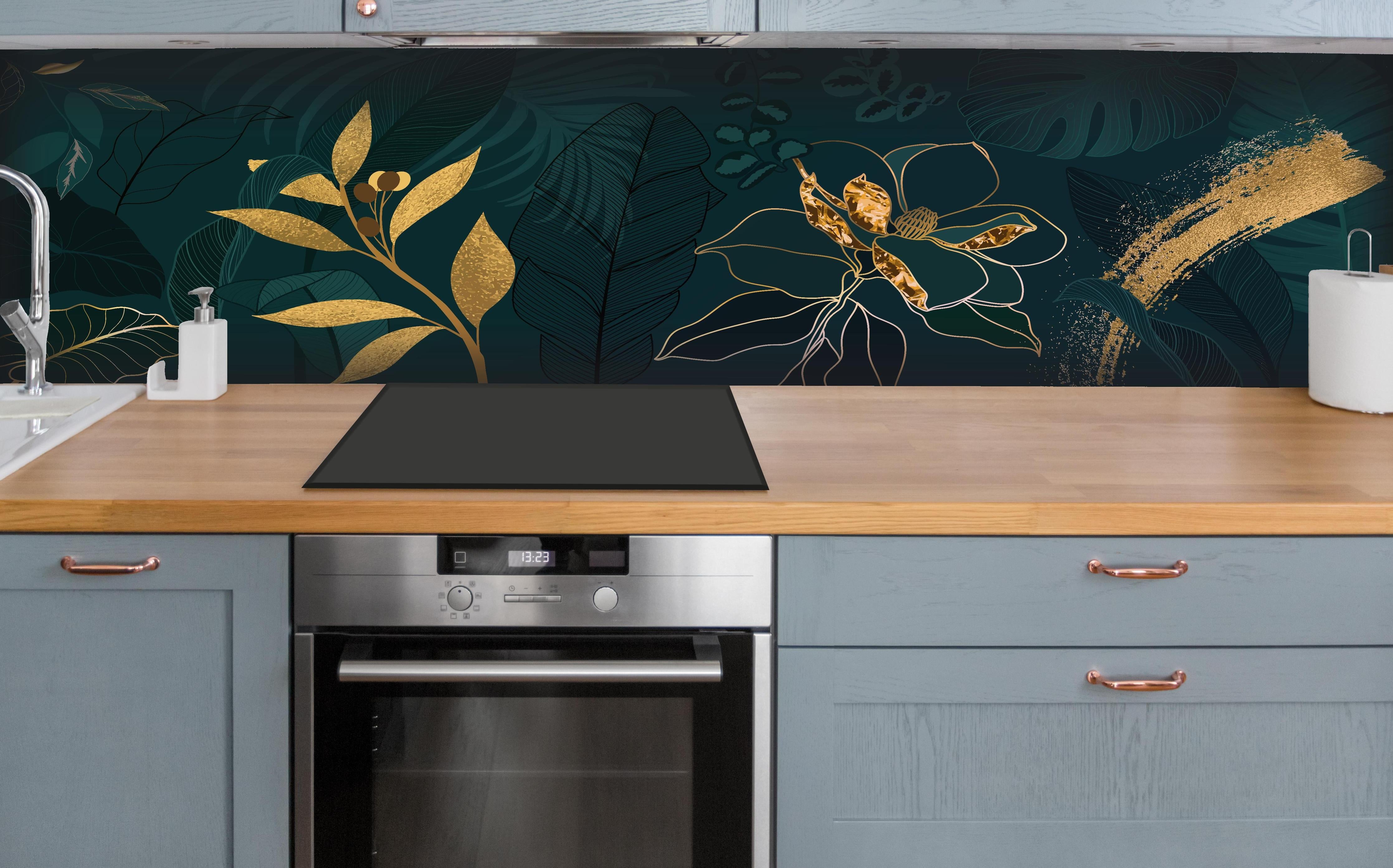 Küche - Dekoratives Blattwerk Dunkelgrün mit Goldakzenten hinter weißen Hochglanz-Küchenregalen und schwarzem Wasserhahn