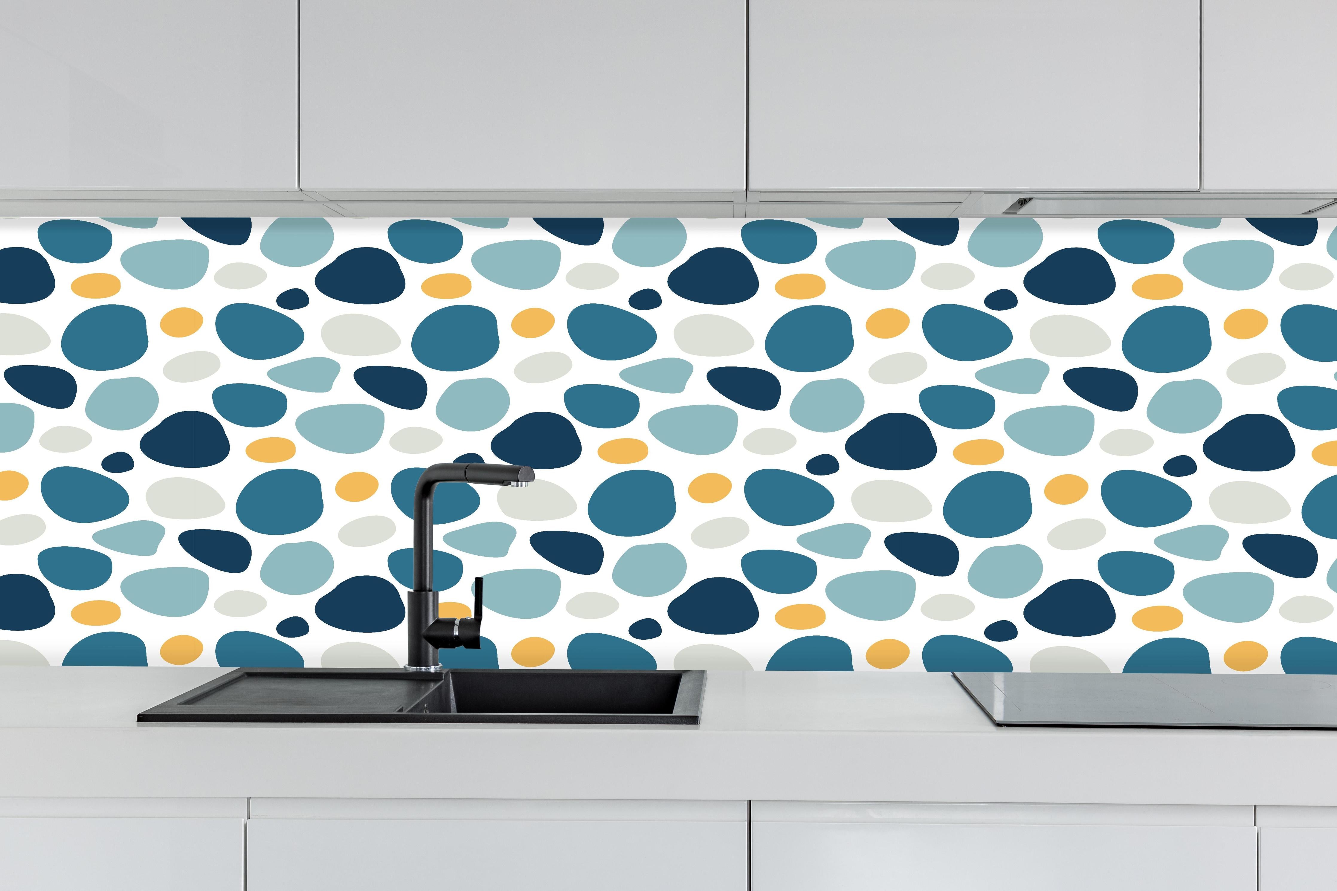 Küche - Dekoratives Blau-Weiß-Oranges Designmuster hinter weißen Hochglanz-Küchenregalen und schwarzem Wasserhahn