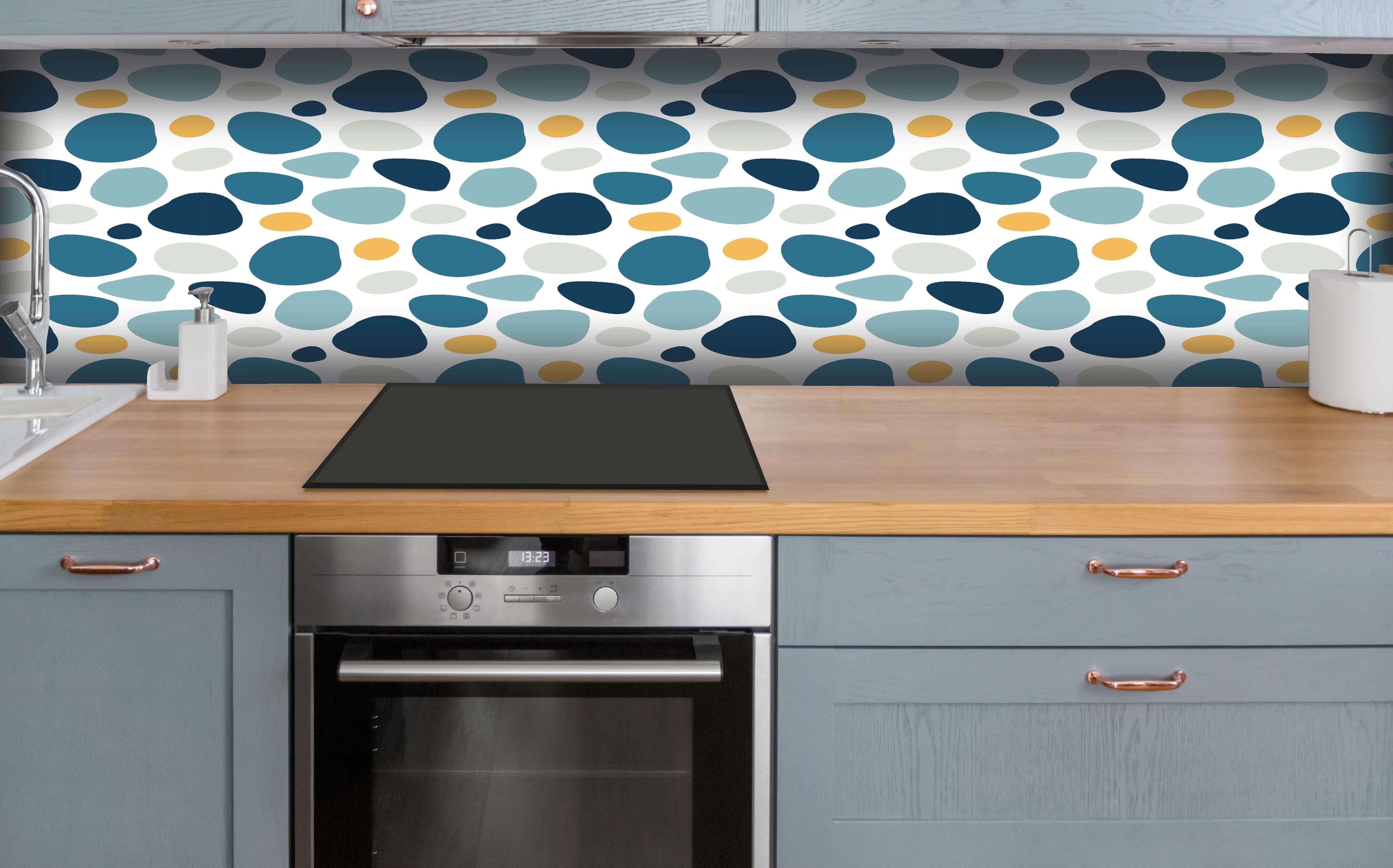 Küche - Dekoratives Blau-Weiß-Oranges Designmuster hinter weißen Hochglanz-Küchenregalen und schwarzem Wasserhahn