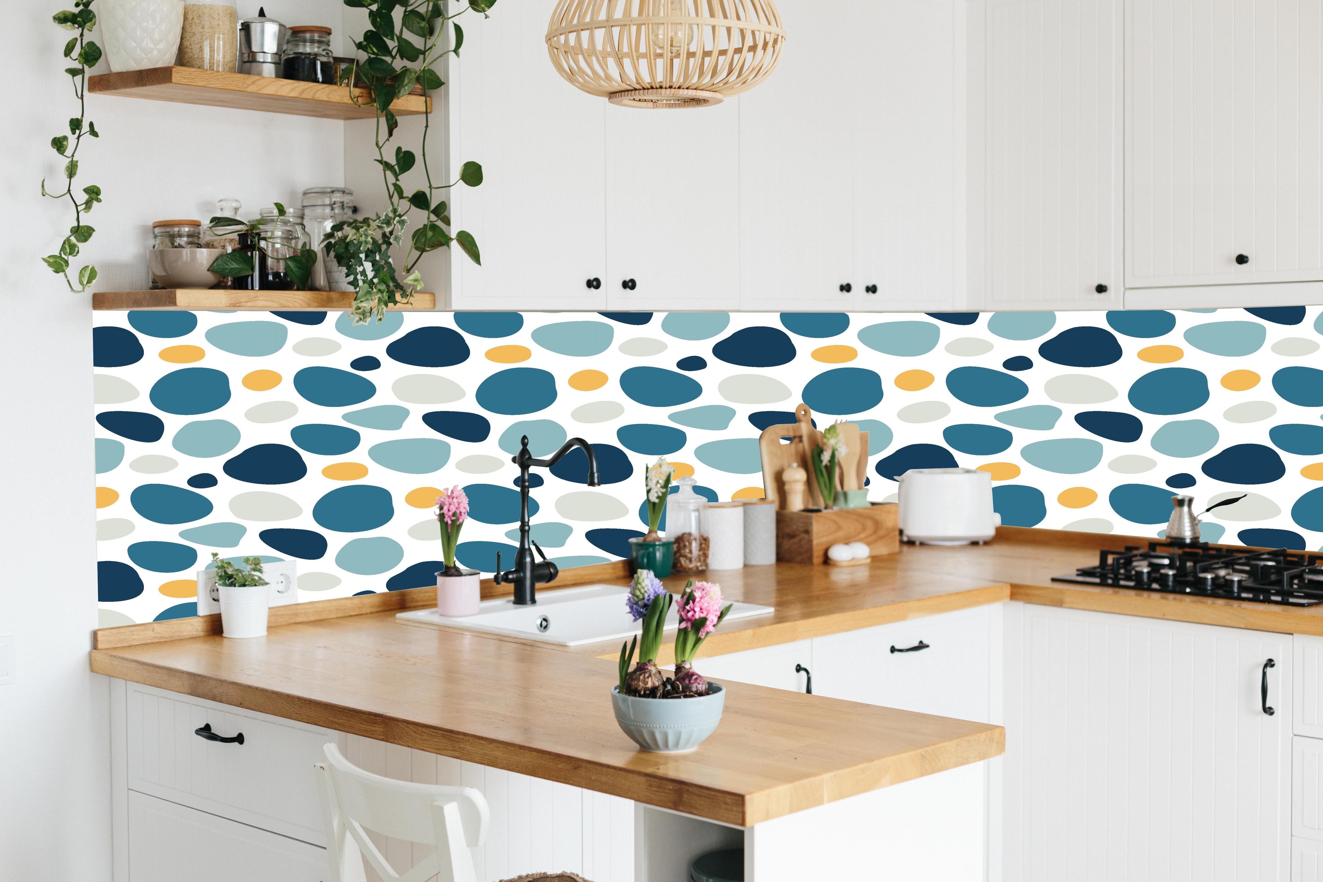 Küche - Dekoratives Blau-Weiß-Oranges Designmuster hinter weißen Hochglanz-Küchenregalen und schwarzem Wasserhahn