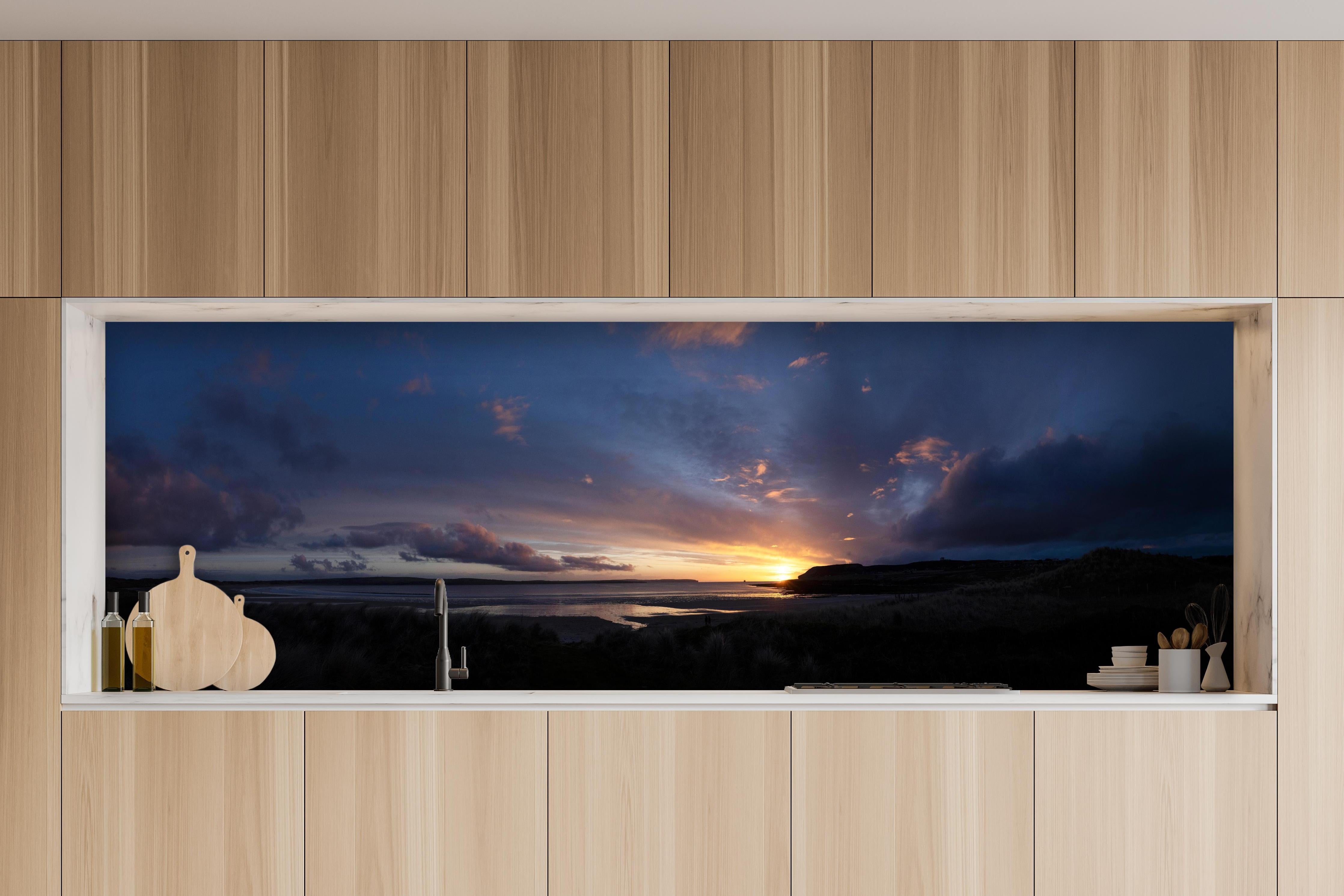 Küche - Ein malerischer Sonnenuntergang über einem ruhigen See, die Wolken leuchten in verschiedenen Blau- und Orangetönen hinter weißen Hochglanz-Küchenregalen und schwarzem Wasserhahn