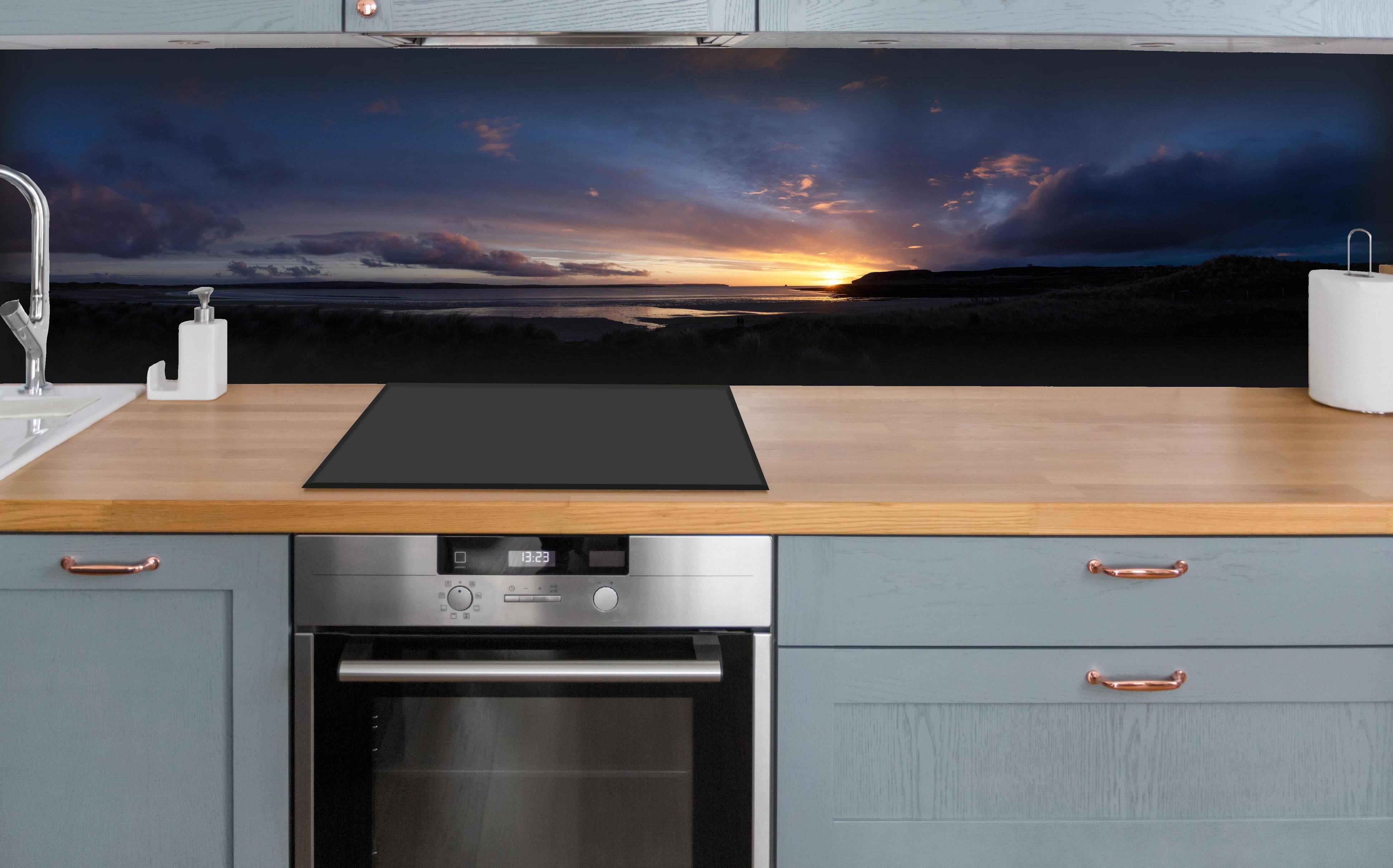 Küche - Ein malerischer Sonnenuntergang über einem ruhigen See, die Wolken leuchten in verschiedenen Blau- und Orangetönen hinter weißen Hochglanz-Küchenregalen und schwarzem Wasserhahn