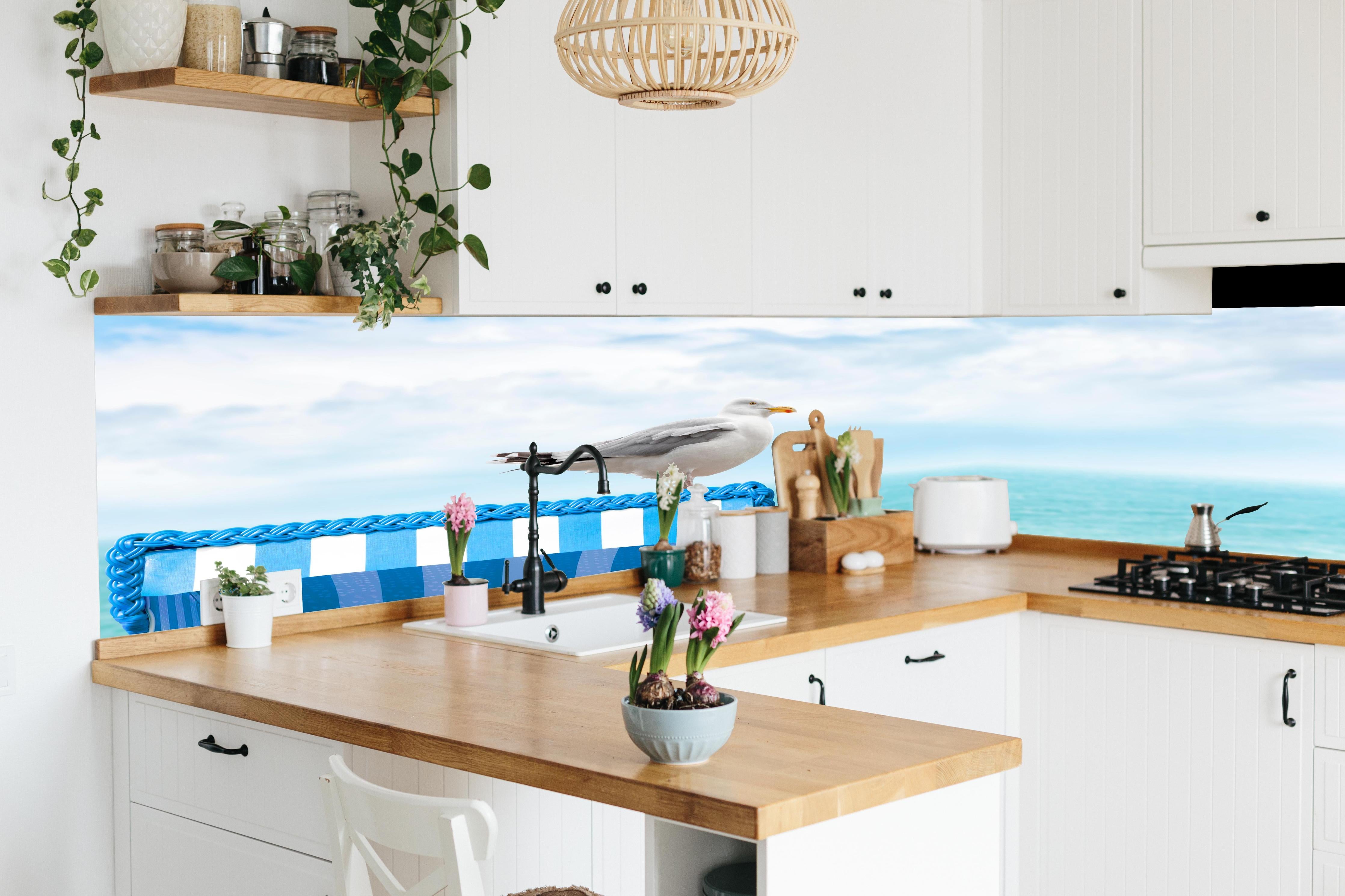 Küche - Elegant Seagull Perched on Blue Beach Chair by the Tranquil Ocean hinter weißen Hochglanz-Küchenregalen und schwarzem Wasserhahn