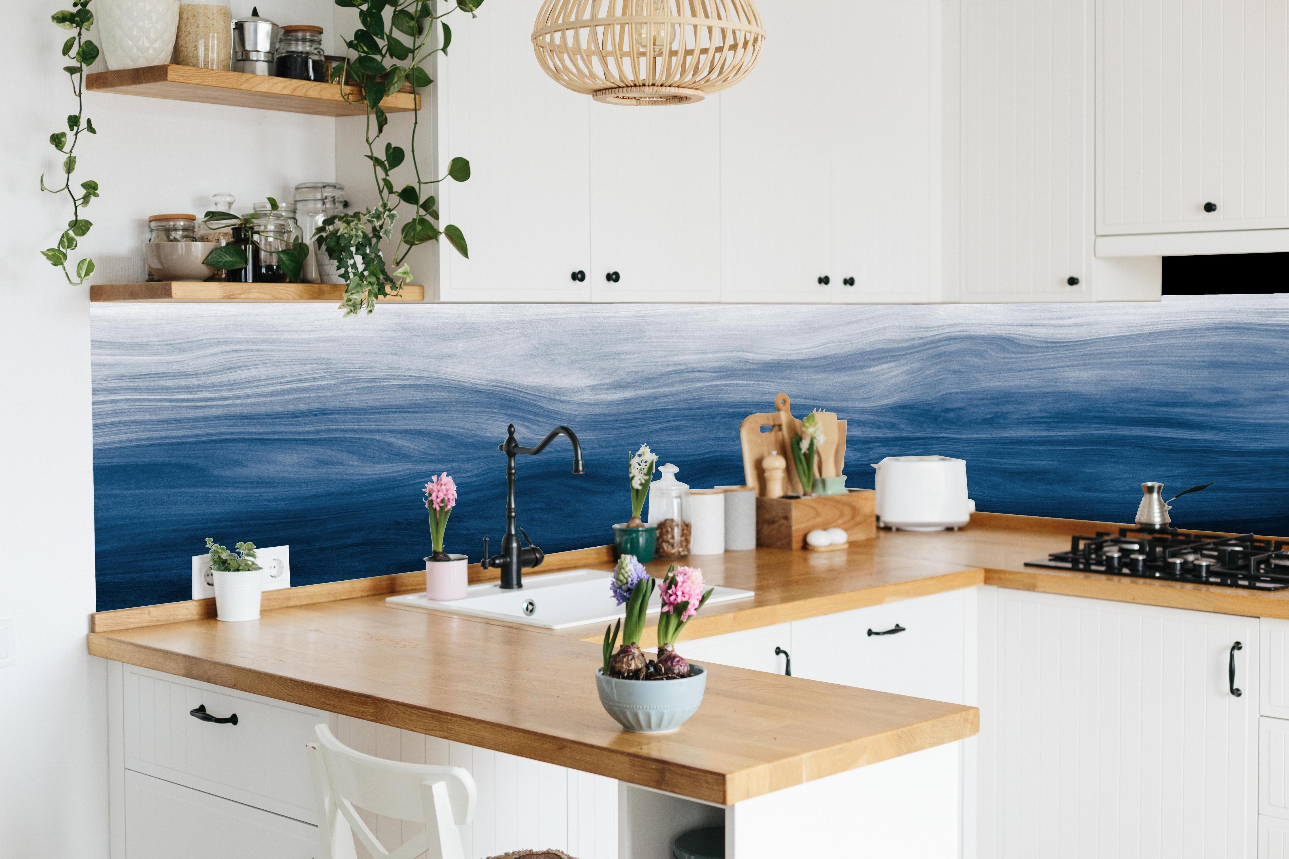 Küche - Elegante abstrakte Wellenstruktur in verschiedenen Blautönen mit Farbverlauf hinter weißen Hochglanz-Küchenregalen und schwarzem Wasserhahn