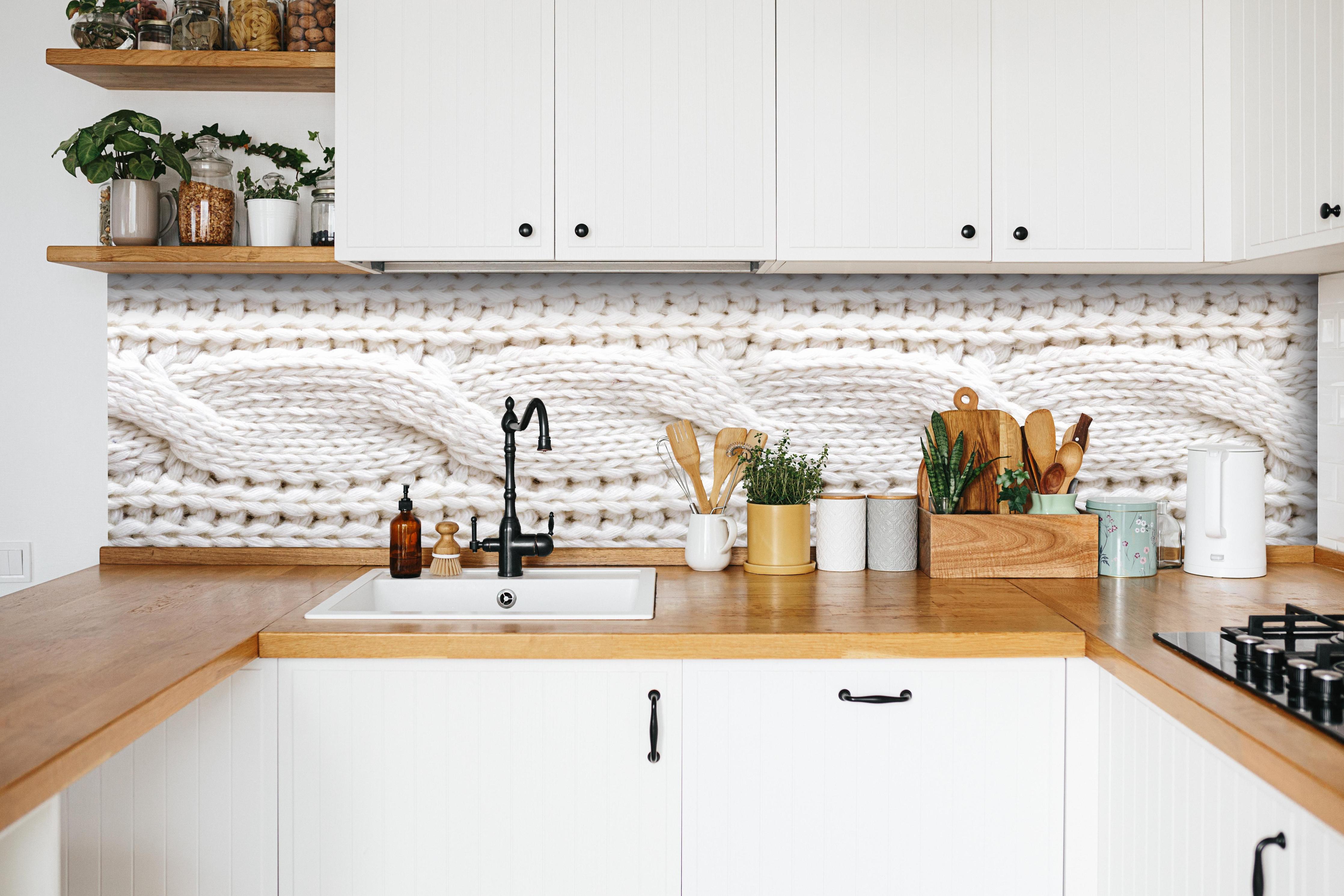 Küche - Elegante weiße Stricktextur aus Wolle hinter weißen Hochglanz-Küchenregalen und schwarzem Wasserhahn