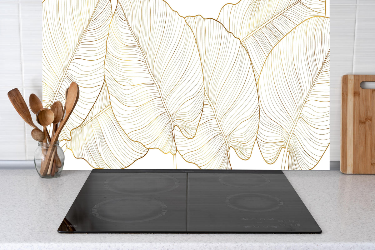 Küche - Elegantes Blatt-Design in Gold und Weiß hinter weißen Hochglanz-Küchenregalen und schwarzem Wasserhahn