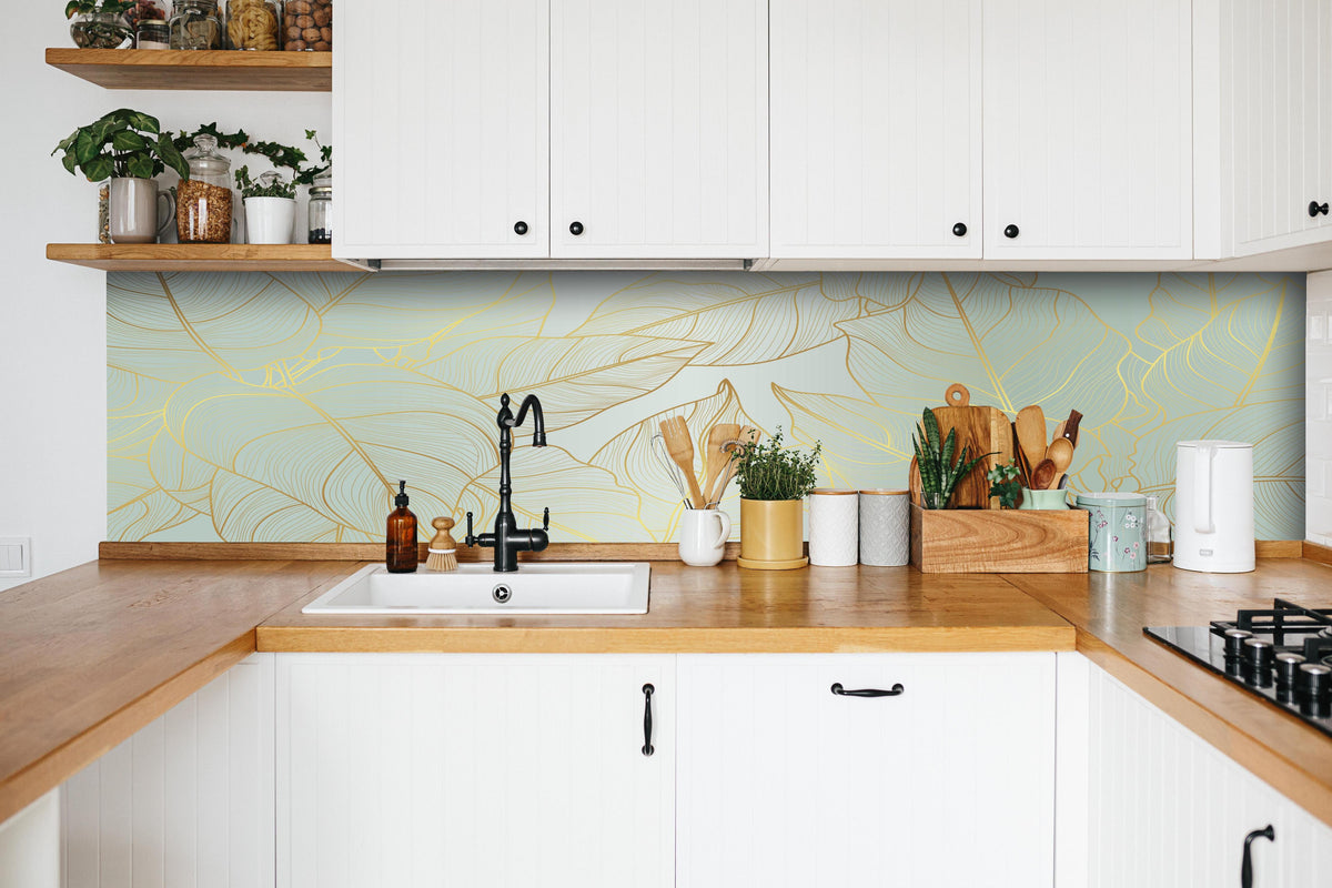 Küche - Elegantes Laub Design in Gold-Beige hinter weißen Hochglanz-Küchenregalen und schwarzem Wasserhahn