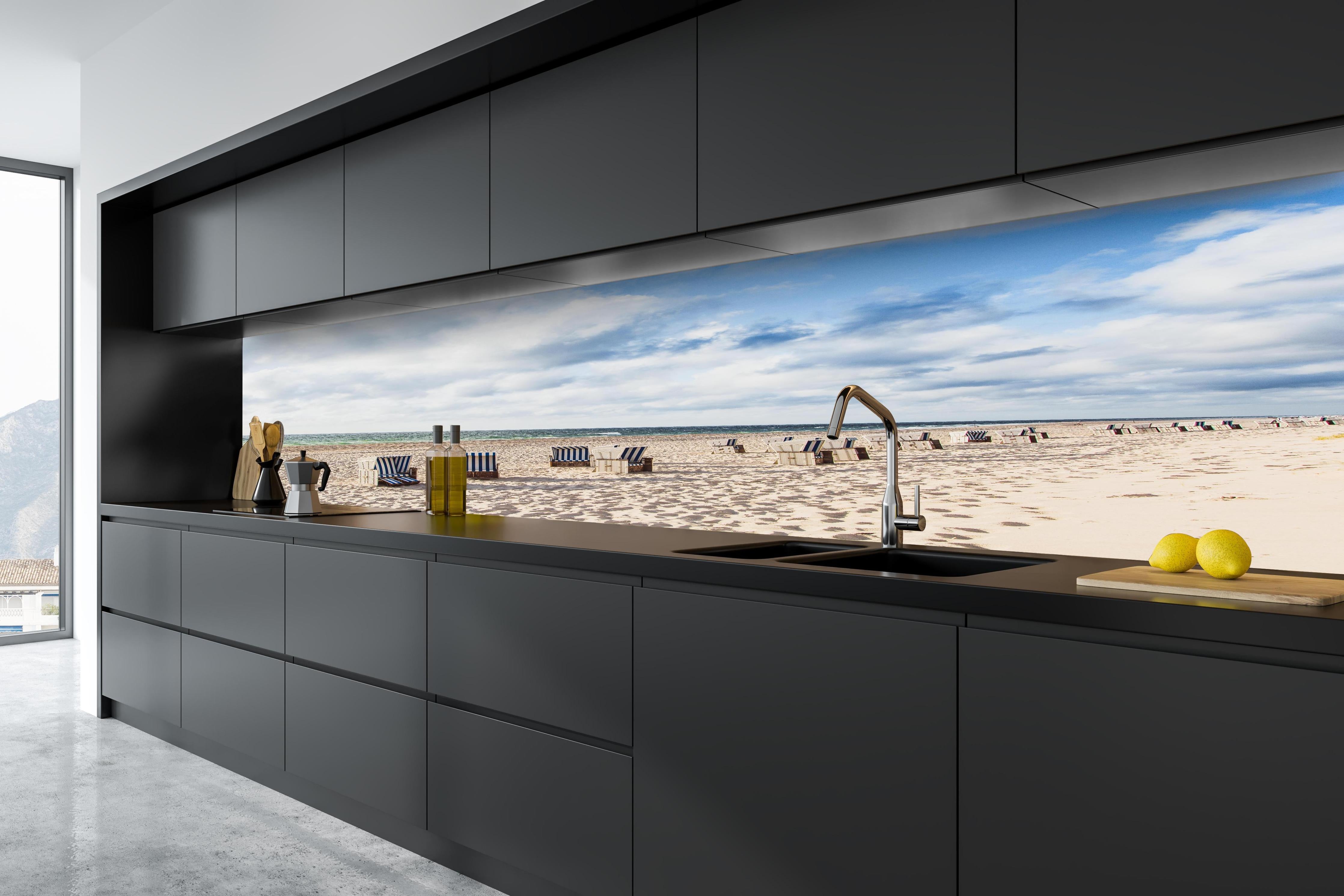 Küche - Entspannte Strandatmosphäre mit blauen und weißen Liegestühlen am Meer hinter weißen Hochglanz-Küchenregalen und schwarzem Wasserhahn