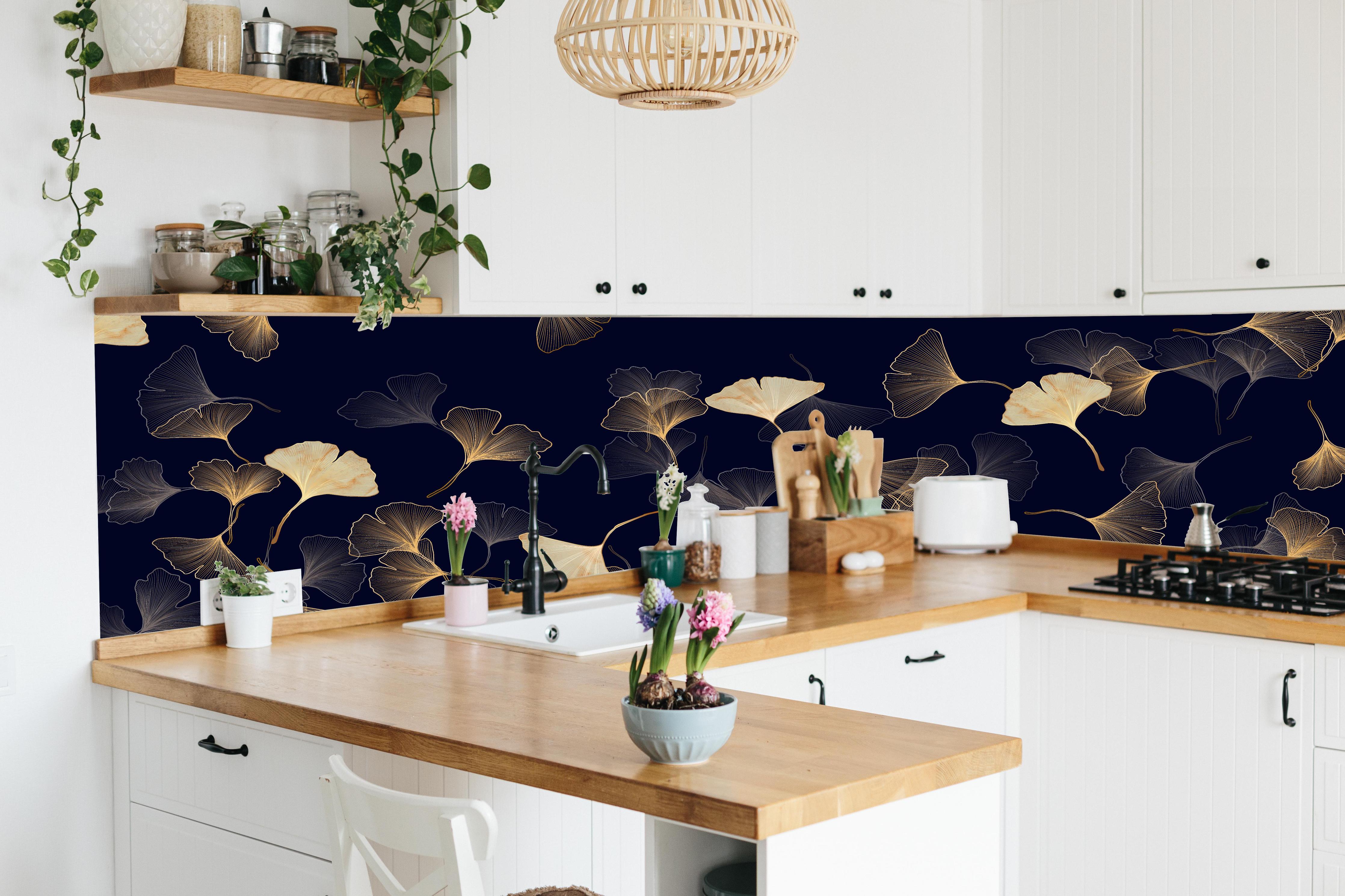 Küche - Exquisite goldene Ginkgo Blätter auf dunklem Hintergrund hinter weißen Hochglanz-Küchenregalen und schwarzem Wasserhahn