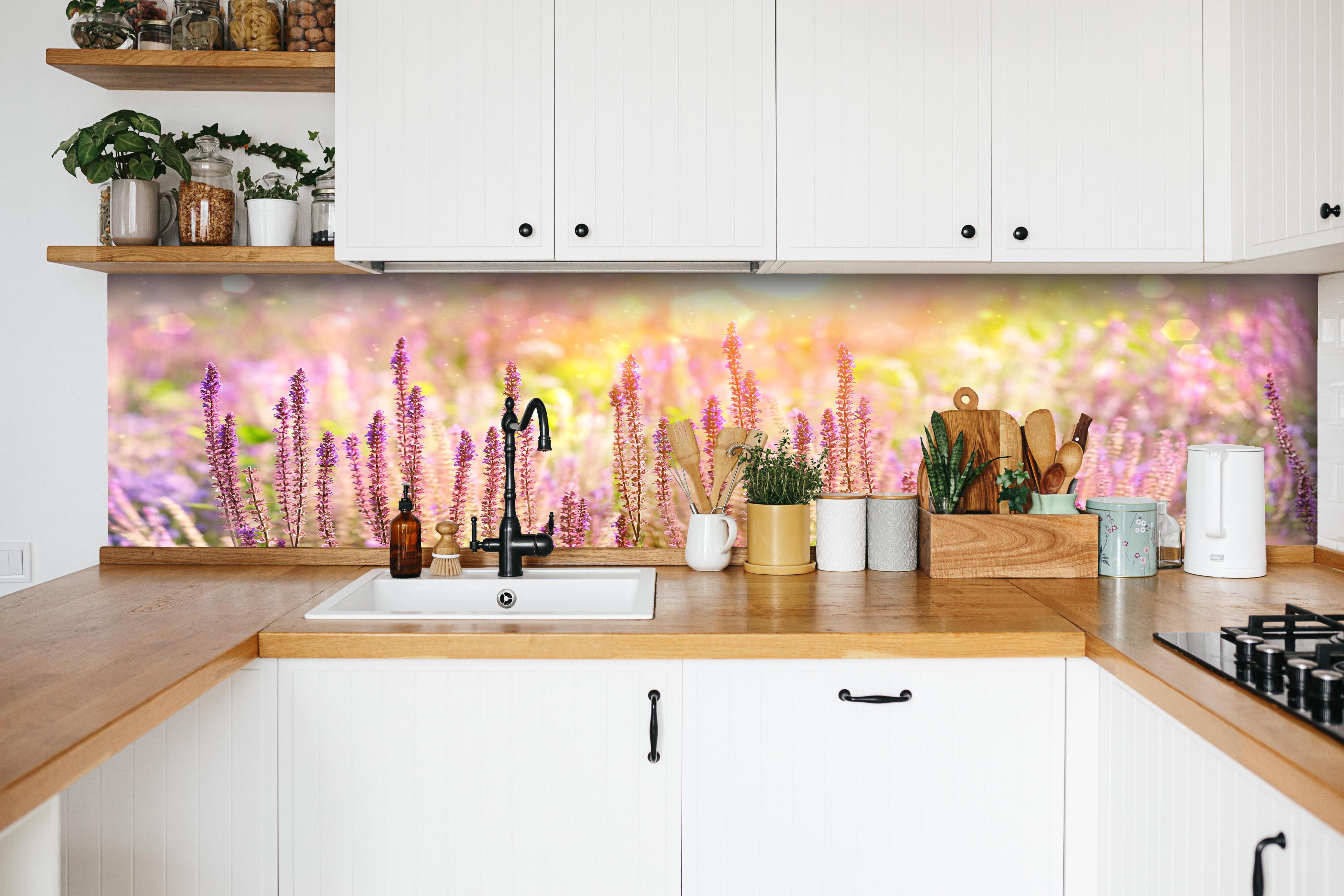 Küche - Farbenfrohe Blüten der Ziersalbei-Pflanzen hinter weißen Hochglanz-Küchenregalen und schwarzem Wasserhahn