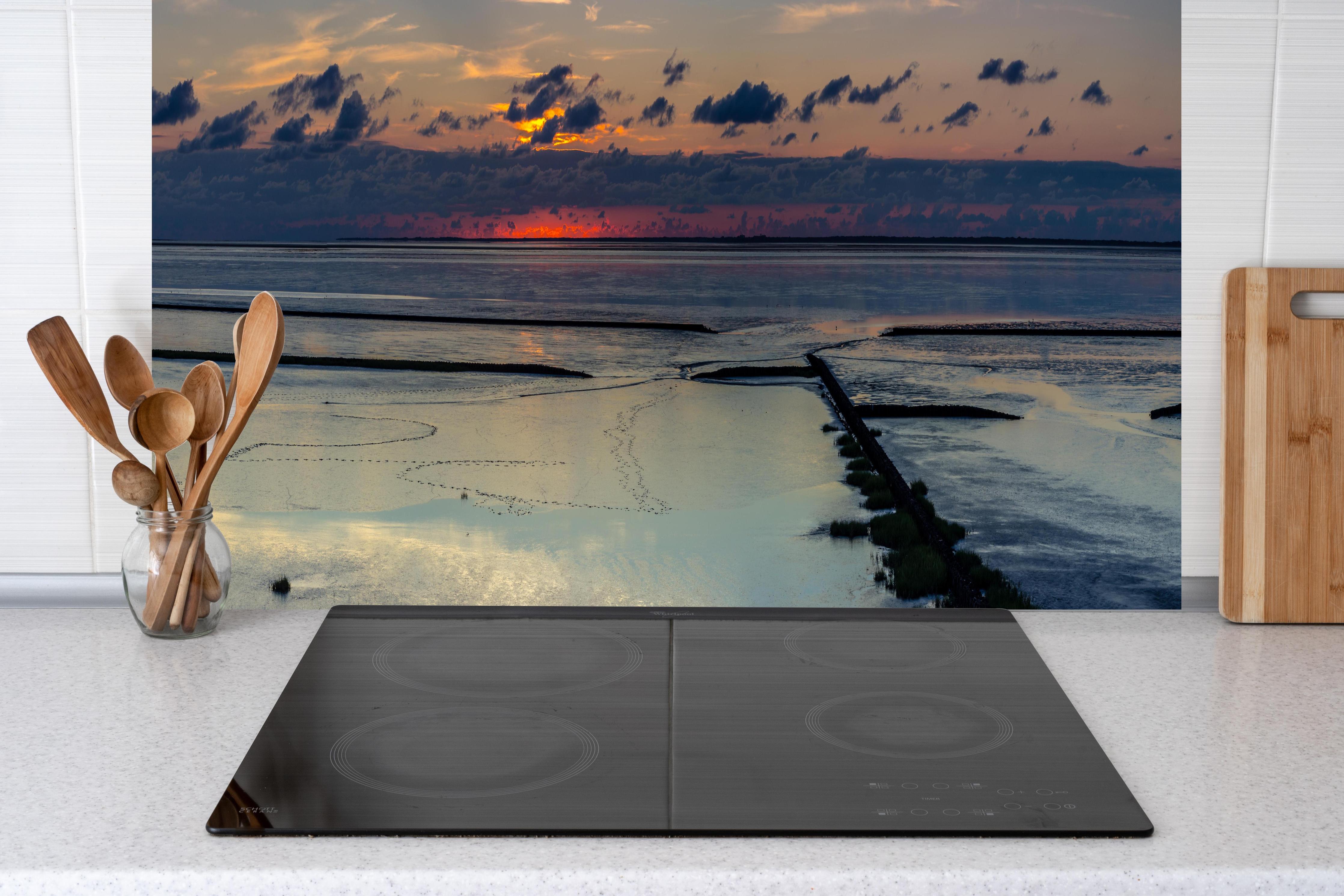 Küche - Faszinierender Sonnenuntergang über einem stillen Gewässer hinter weißen Hochglanz-Küchenregalen und schwarzem Wasserhahn