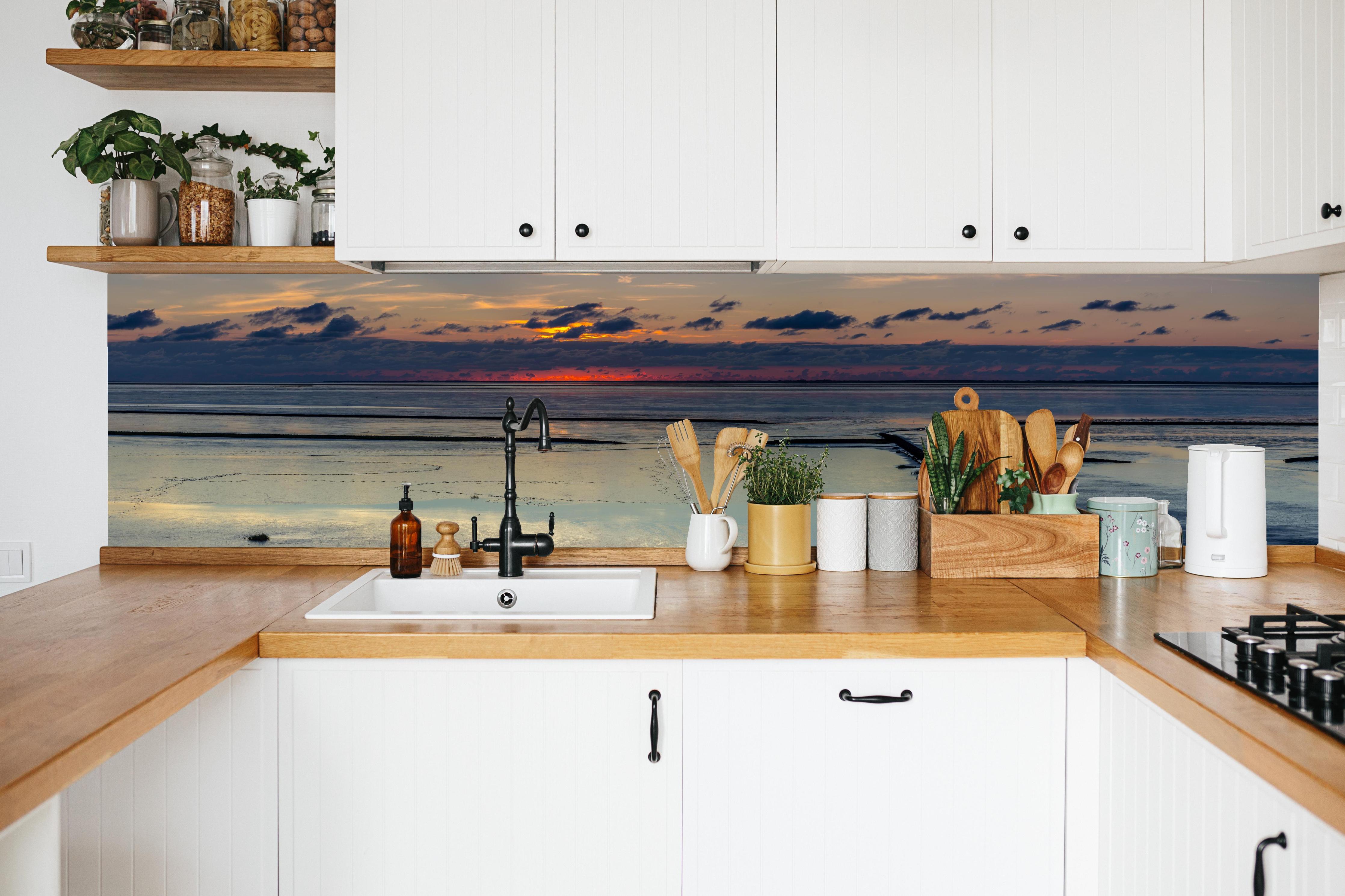 Küche - Faszinierender Sonnenuntergang über einem stillen Gewässer hinter weißen Hochglanz-Küchenregalen und schwarzem Wasserhahn
