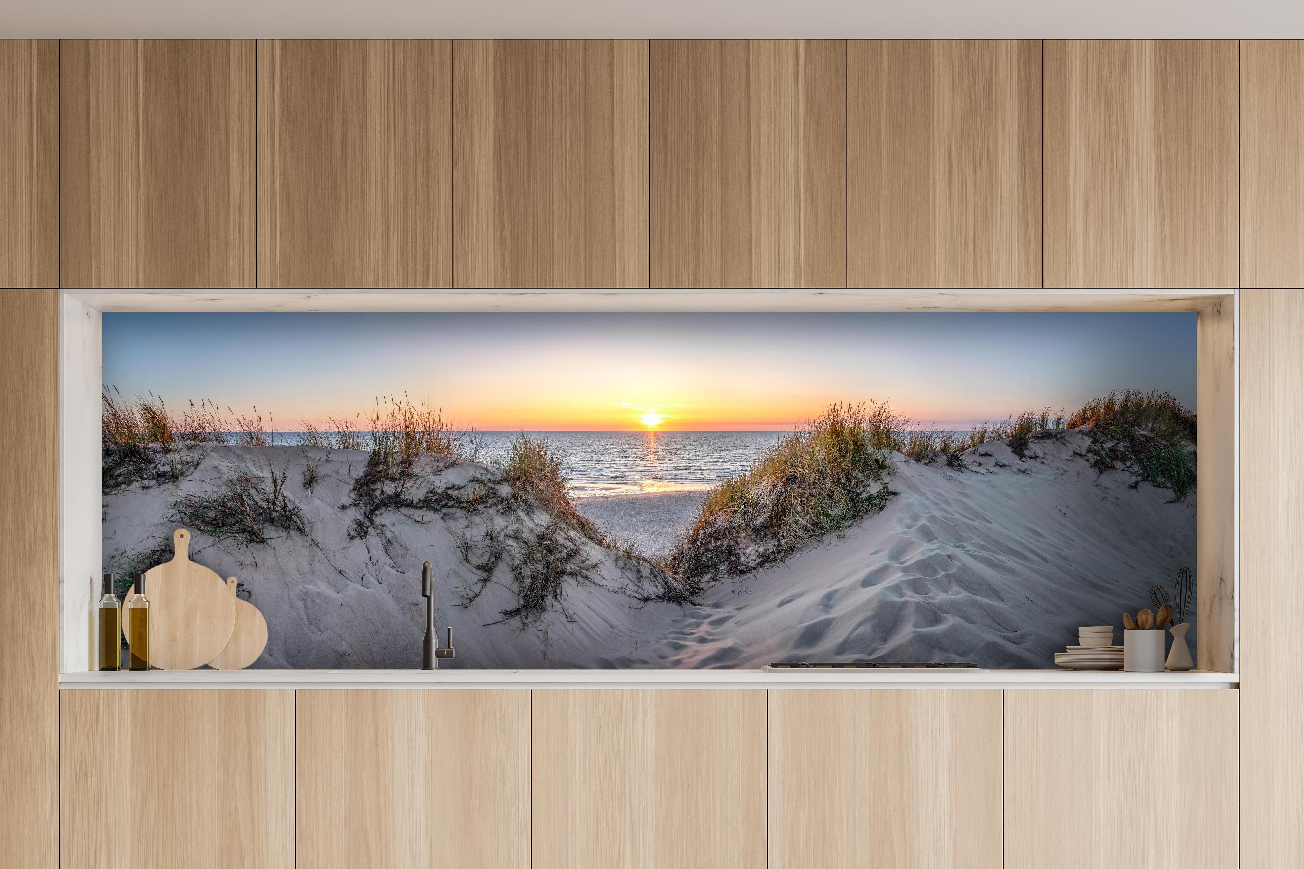Küche - Faszinierender Sonnenuntergang über einer Sanddüne am Meer hinter weißen Hochglanz-Küchenregalen und schwarzem Wasserhahn
