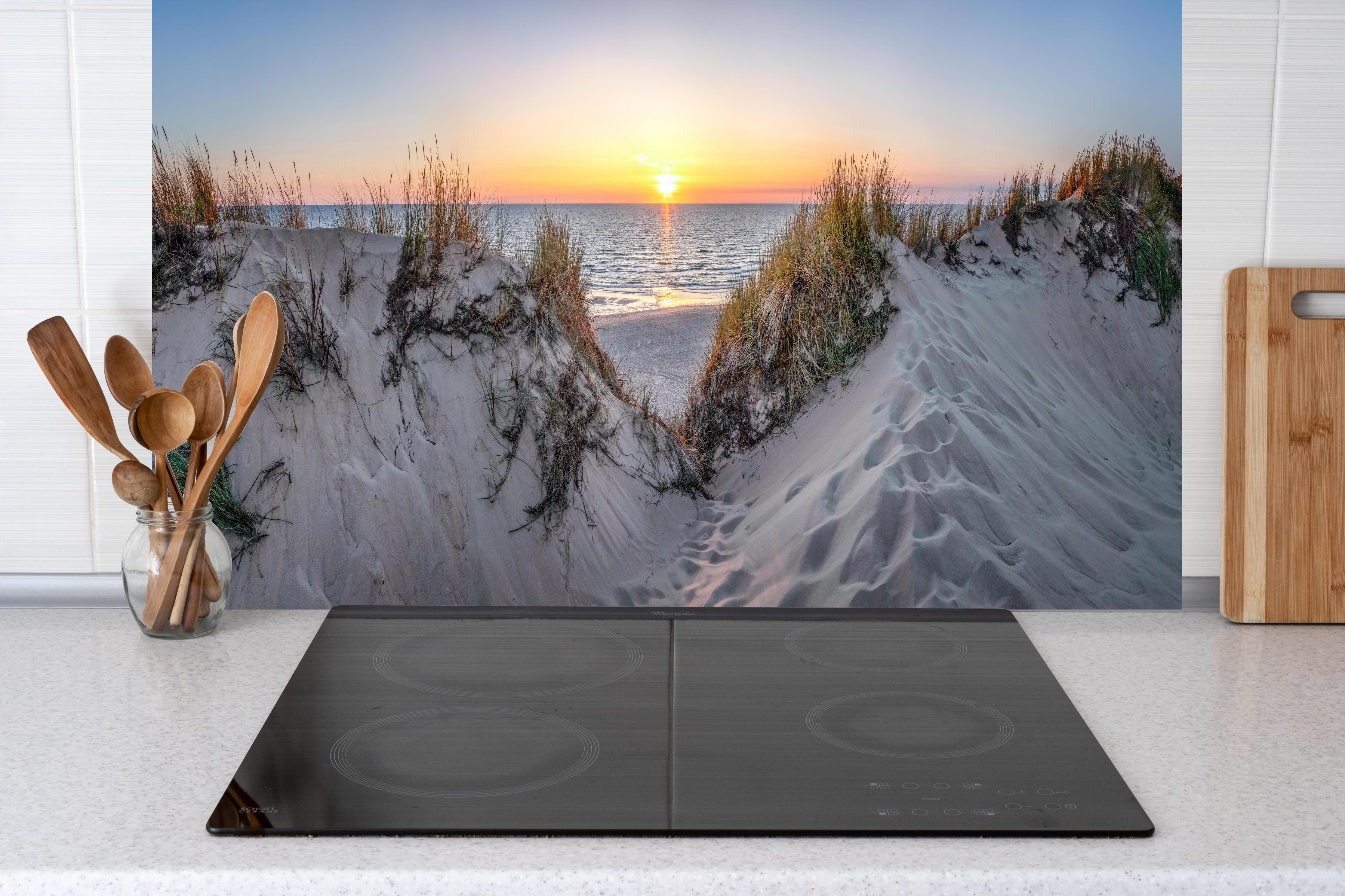 Küche - Faszinierender Sonnenuntergang über einer Sanddüne am Meer hinter weißen Hochglanz-Küchenregalen und schwarzem Wasserhahn