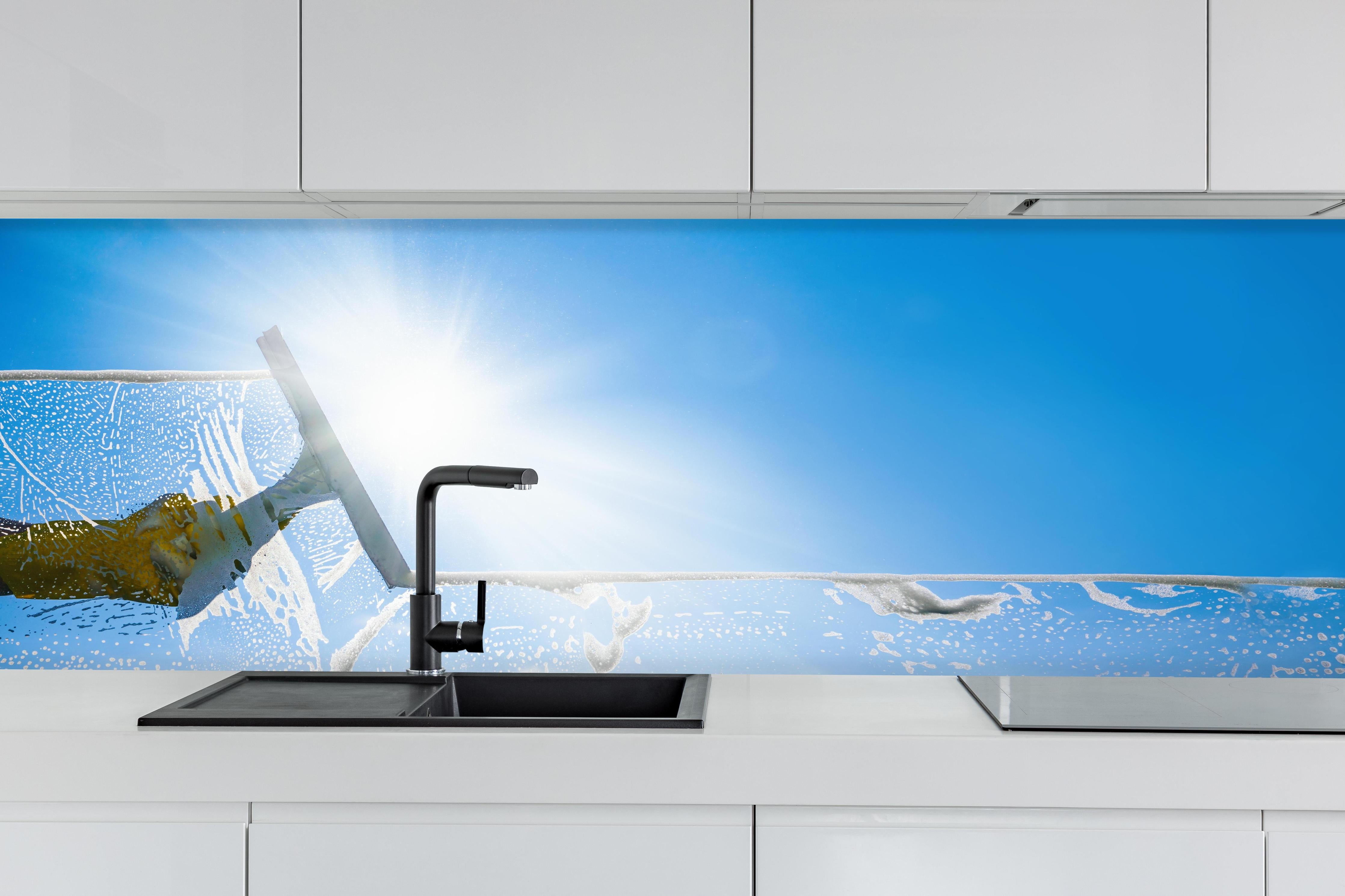 Küche - Fensterputzer mit Abzieher und strahlendem Himmel hinter weißen Hochglanz-Küchenregalen und schwarzem Wasserhahn